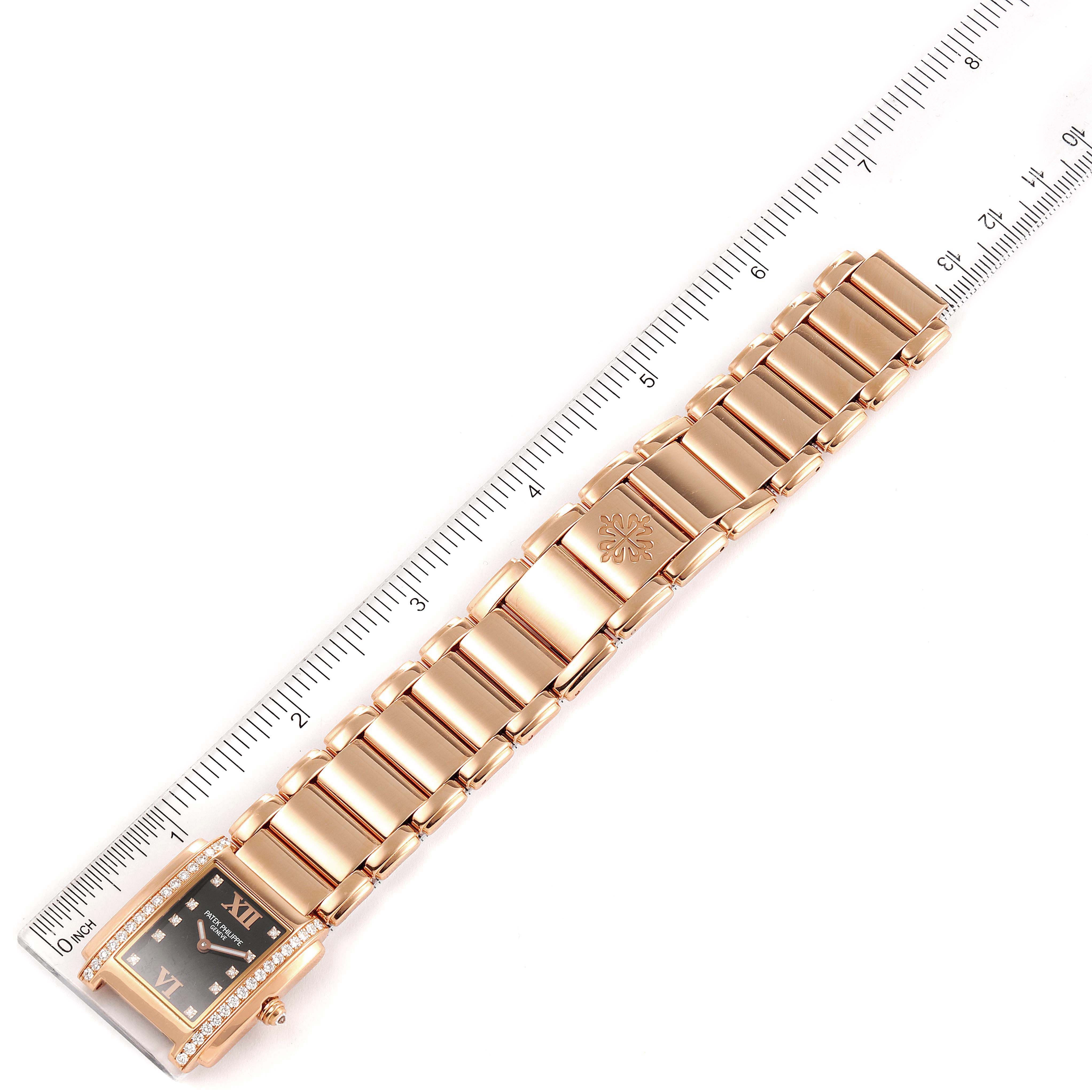 The image shows the front view of a Patek Philippe Twenty-4 4910/11R Women's Rose Gold Black Dial 4910/11R Women's Rose Gold Black Dial watch, highlighting its bracelet and face against a ruler for scale.