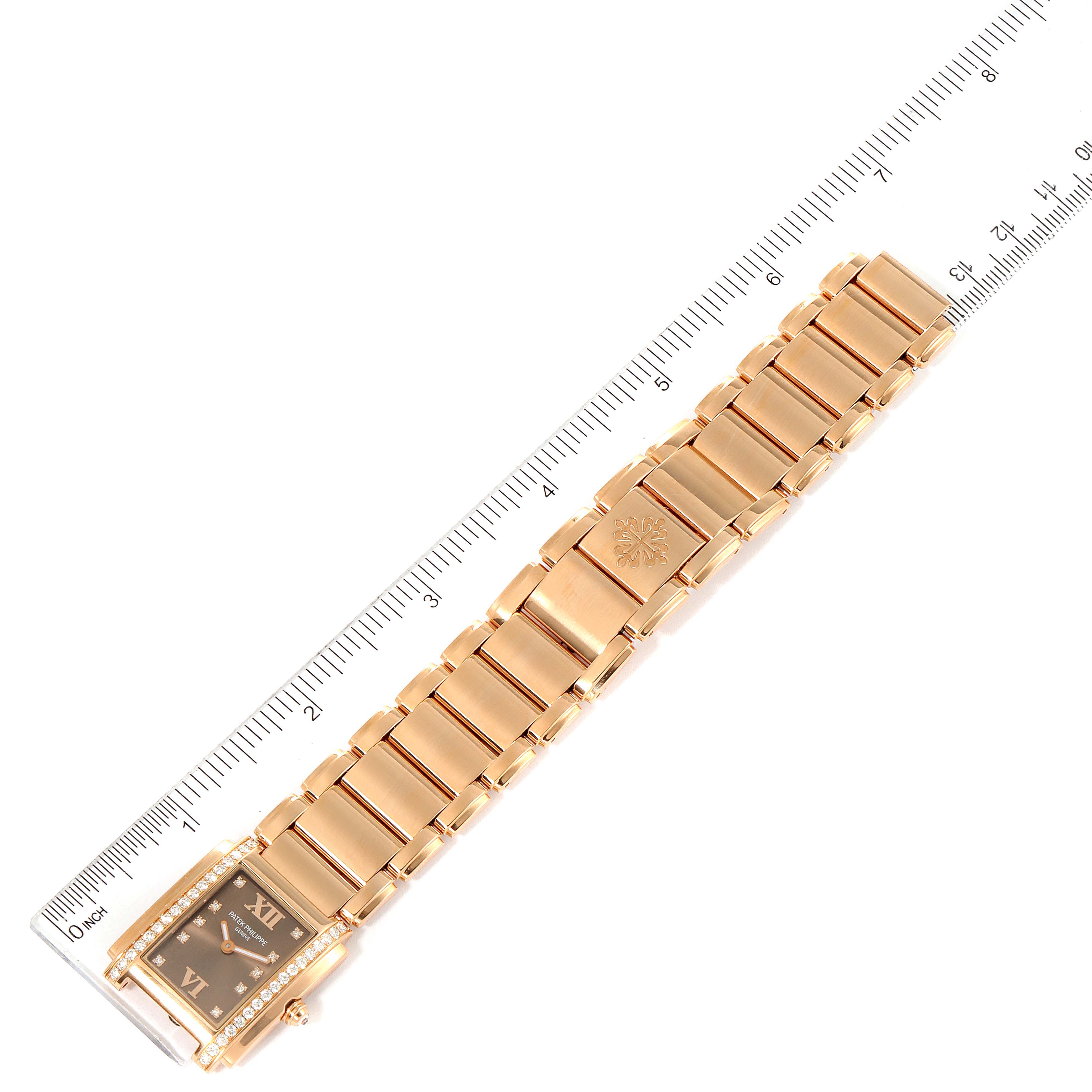 The image shows a Patek Philippe Twenty-4 4910/11R Women's Rose Gold Brown Dial 4910/11R Women's Rose Gold Brown Dial watch laid flat with its bracelet extended, placed next to a ruler for size reference.