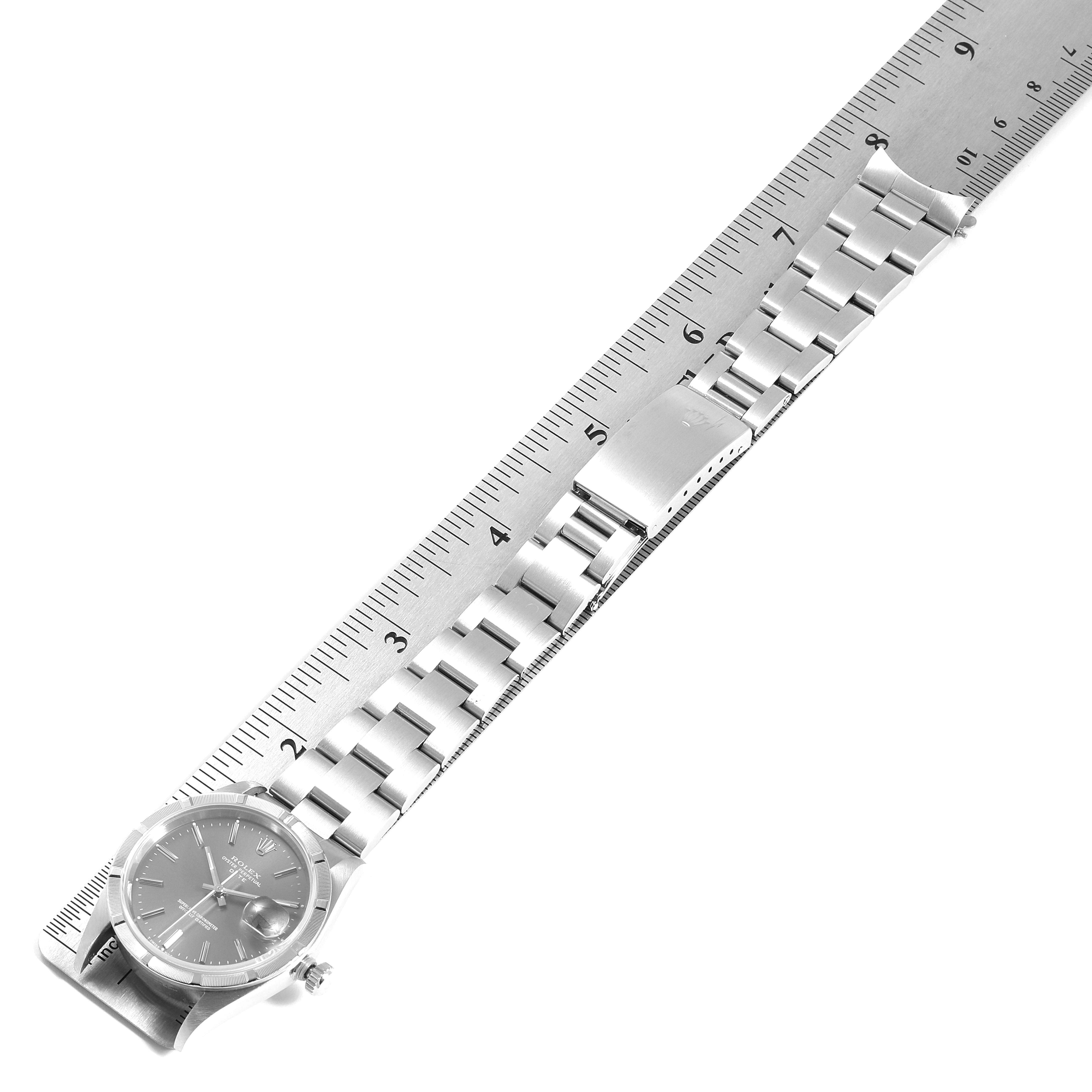 The Rolex Date 15210 Men's Stainless Steel Grey Dial 15210 Men's Stainless Steel Grey Dial model watch is shown diagonally from an overhead view, including the full bracelet and part of a measuring ruler.