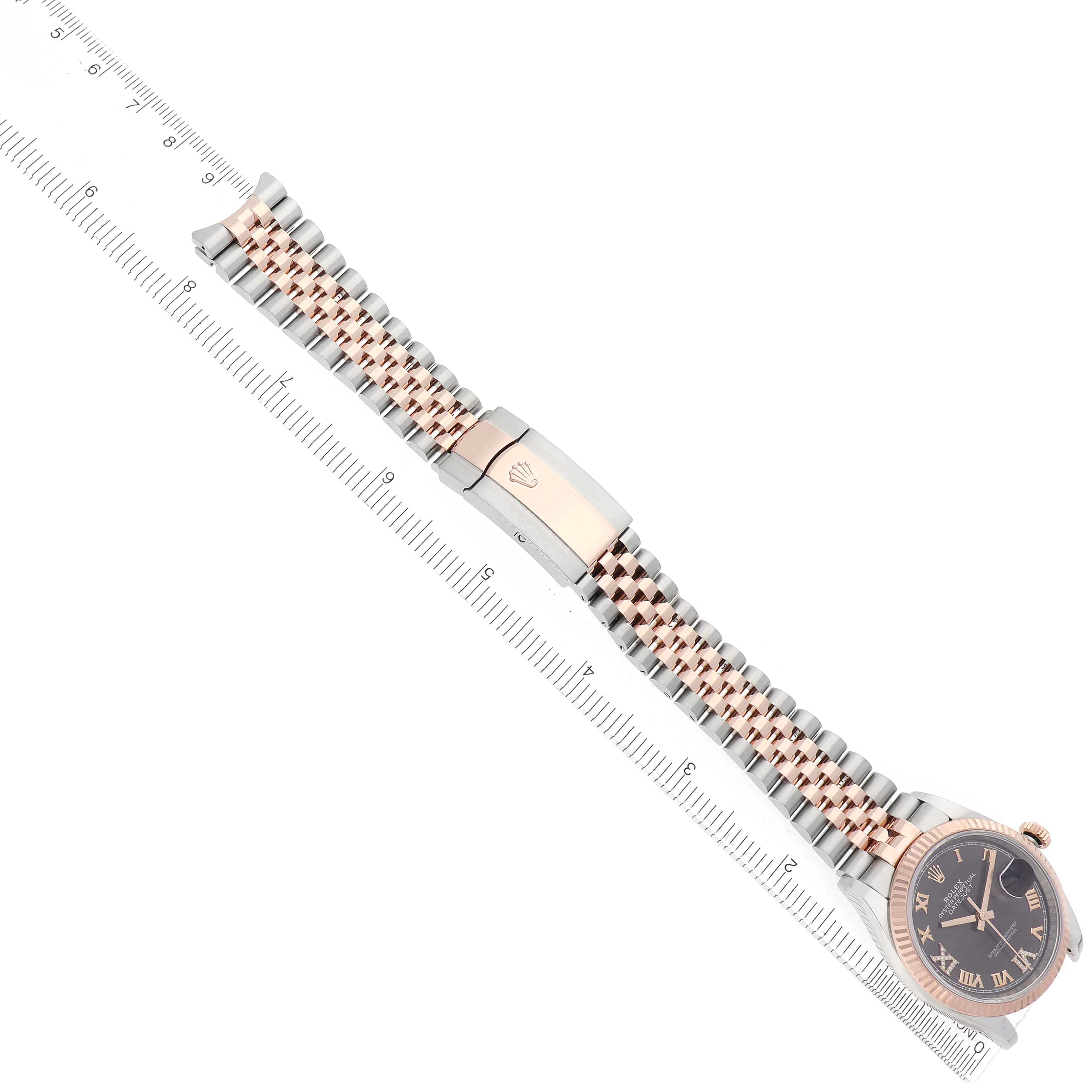 The Rolex Datejust 126231 Men
s Steel and Gold (two tone) Brown Dial watch is shown from a top-down angle, highlighting the band, clasp, and face against a ruler for scale.