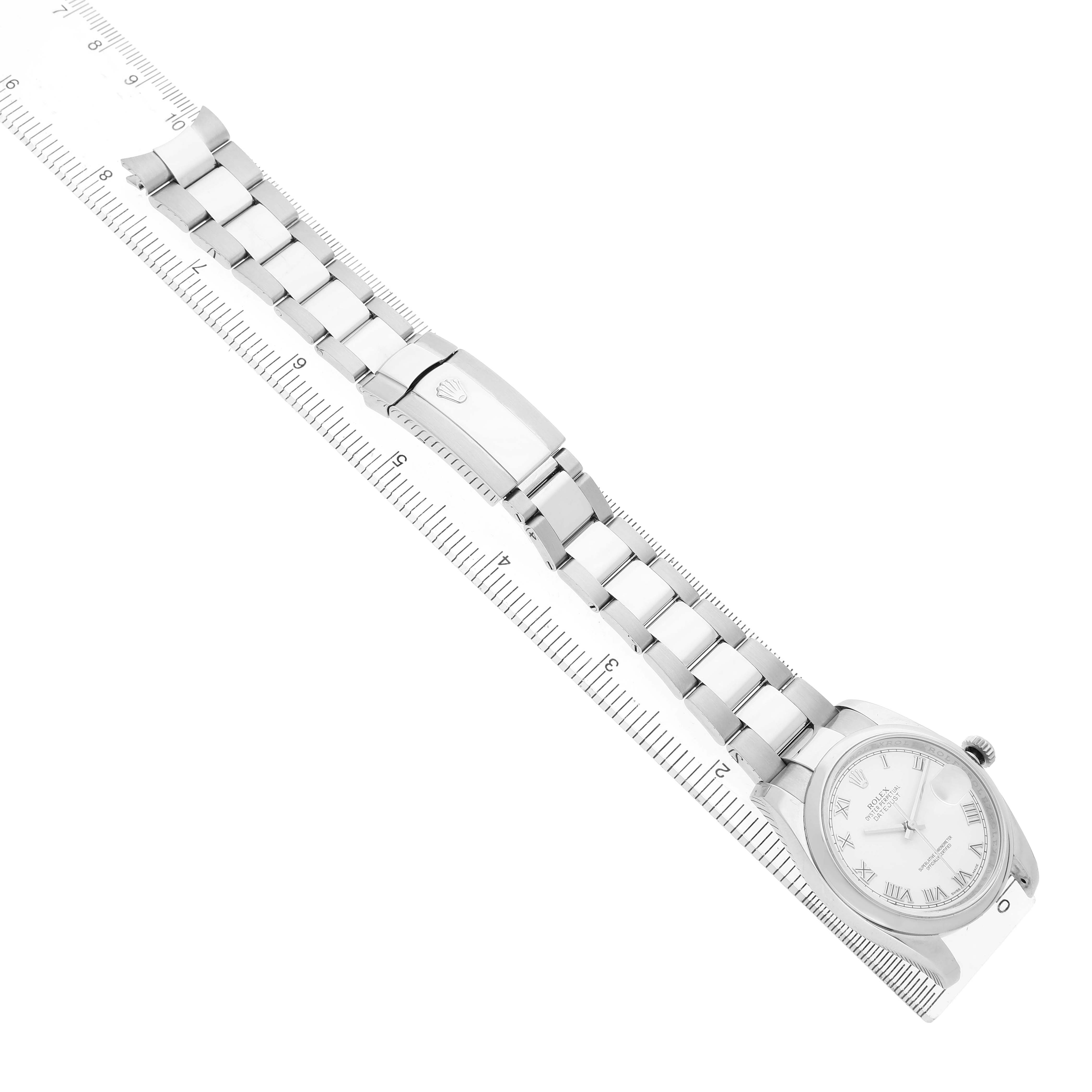 The Rolex Datejust 116200 Men's Stainless Steel White Dial watch is shown from a top angle, highlighting its bracelet, clasp, and face placed next to a ruler.