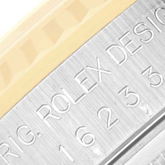 This is a close-up angle showing the engraving "ORIG. ROLEX DESIGN" and part of the fluted bezel on the Rolex Datejust 16233 Men's Steel and Gold (two tone) Blue Dial 16233 Men's Steel and Gold (two tone) Blue Dial model.