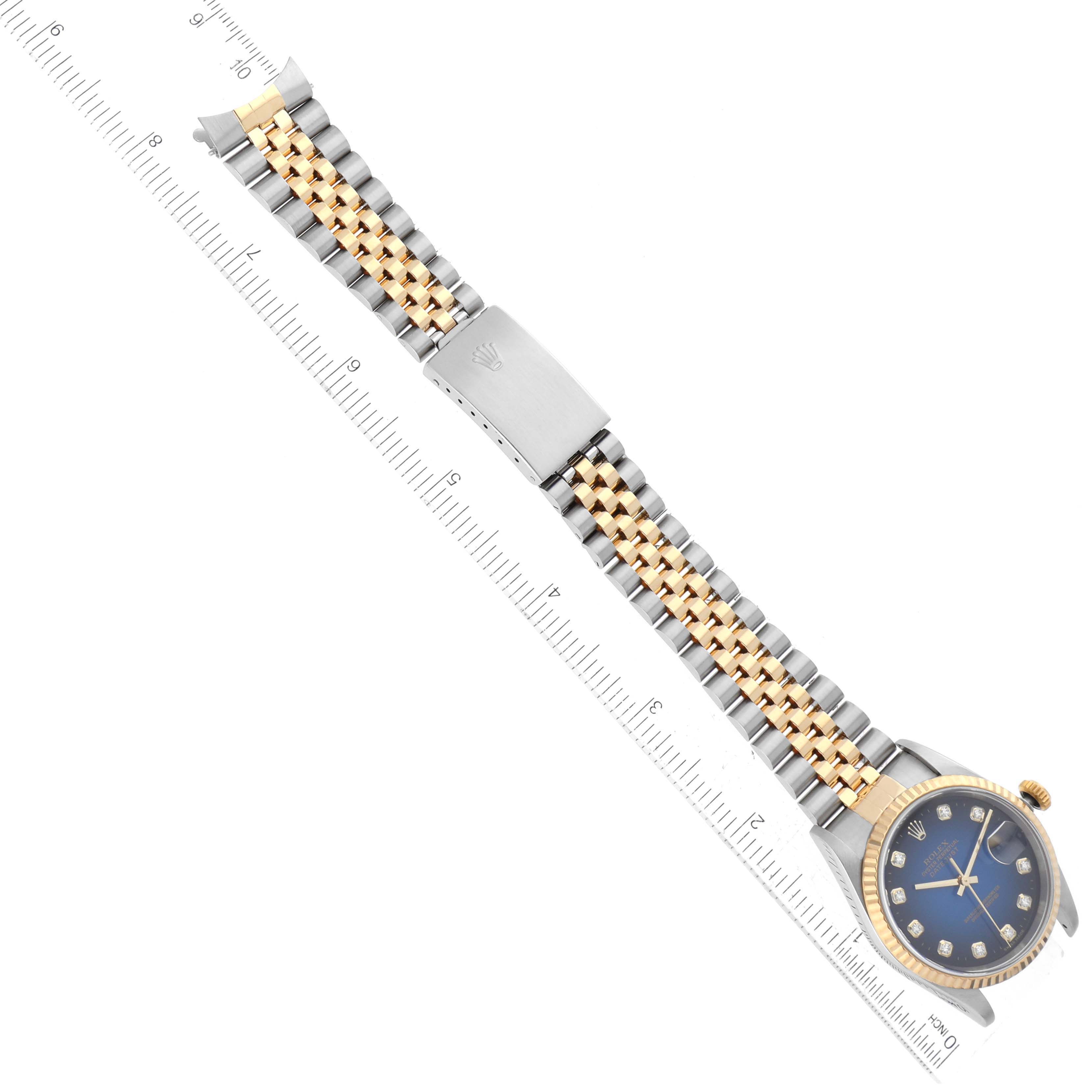 This top-down photo shows a Rolex Datejust 16233 Men's Steel and Gold (two tone) Blue Dial 16233 Men's Steel and Gold (two tone) Blue Dial watch with its bracelet extended and aligned next to a ruler for scale.