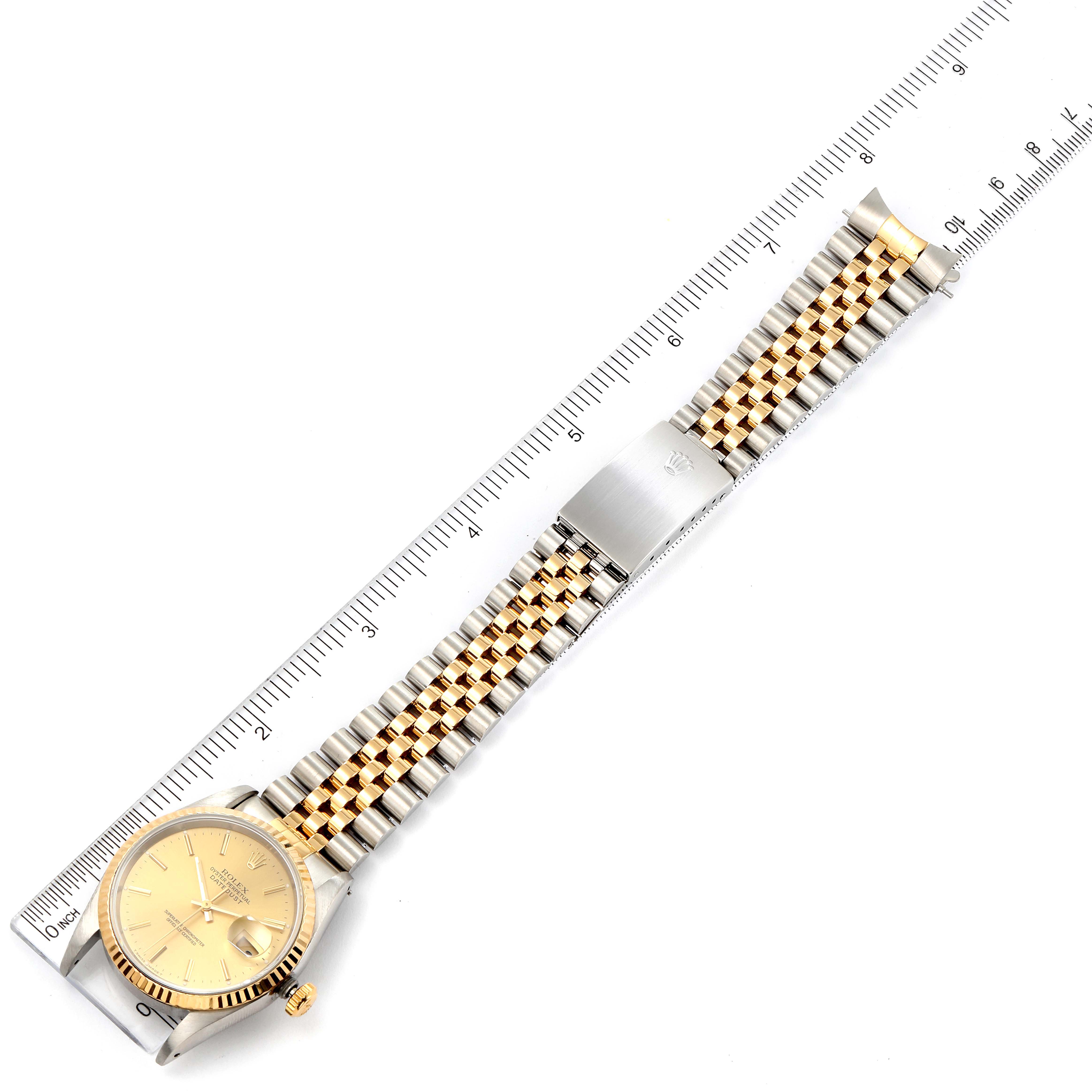 This image shows a top-down view of a Rolex Datejust 16233 Men's Steel and Gold (two tone) Champagne Dial 16233 Men's Steel and Gold (two tone) Champagne Dial watch, displaying its gold dial, fluted bezel, and two-tone bracelet next to a ruler.