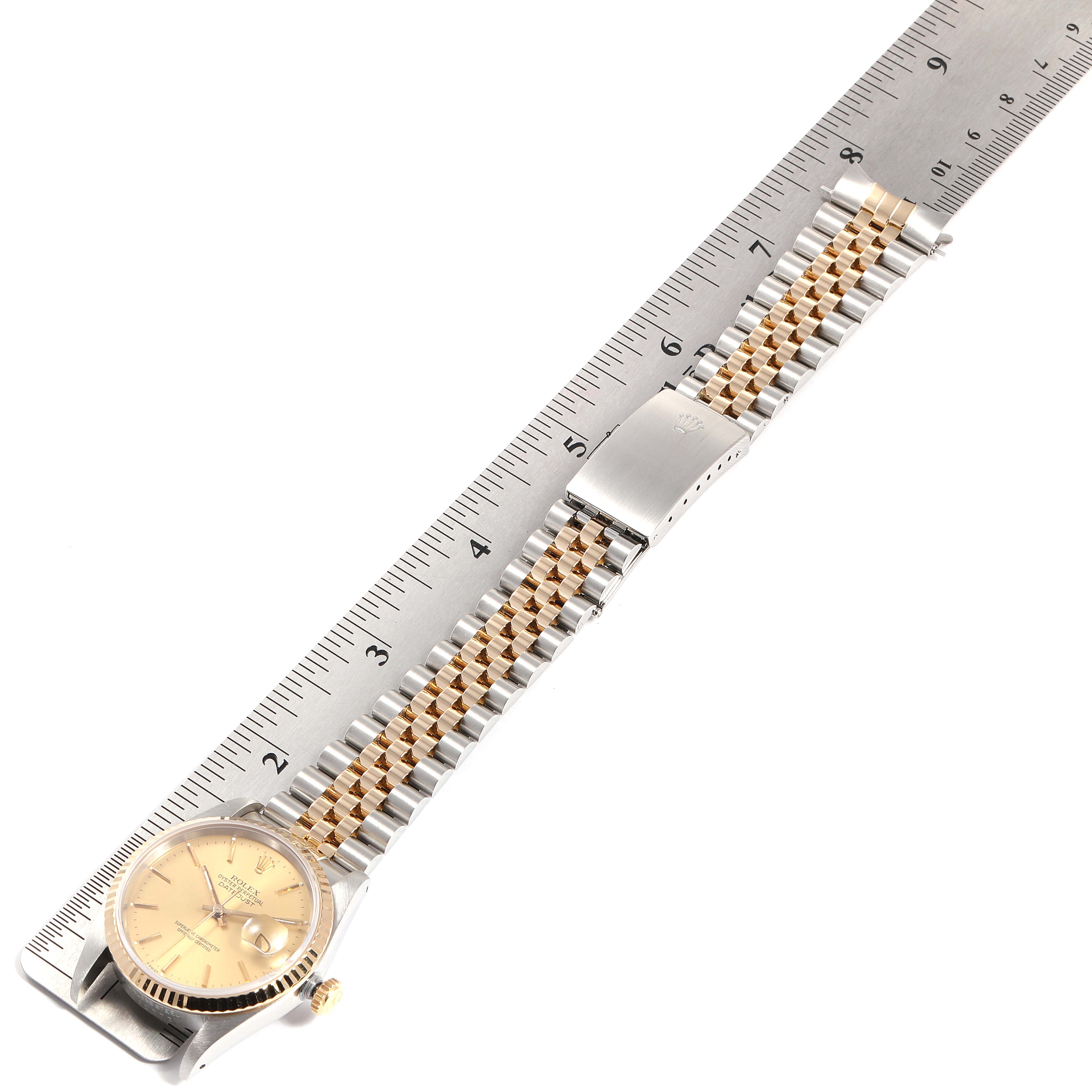 The Rolex Datejust 16233 Men
s Steel and Gold (two tone) Champagne Dial 16233 Men
s Steel and Gold (two tone) Champagne Dial watch is shown from an angled top view, highlighting the face and bracelet beside a ruler for scale.