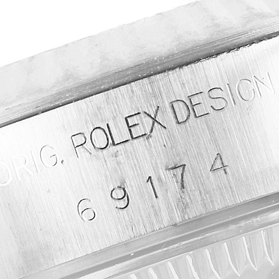 The image shows a close-up of the engraved case side of a Rolex Datejust 69174 Women's Stainless Steel Blue Dial 69174 Women's Stainless Steel Blue Dial watch, highlighting the "ROLEX DESIGN" inscription and model number.