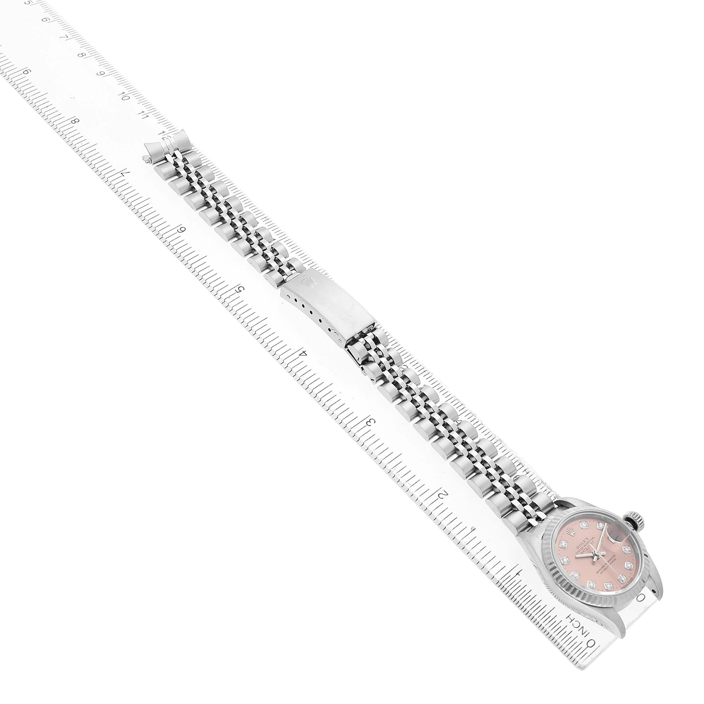 The Rolex Datejust 69174 Women's Stainless Steel Pink Dial watch is shown from a top-down angle, highlighting the bracelet and watch face aligned with a ruler.