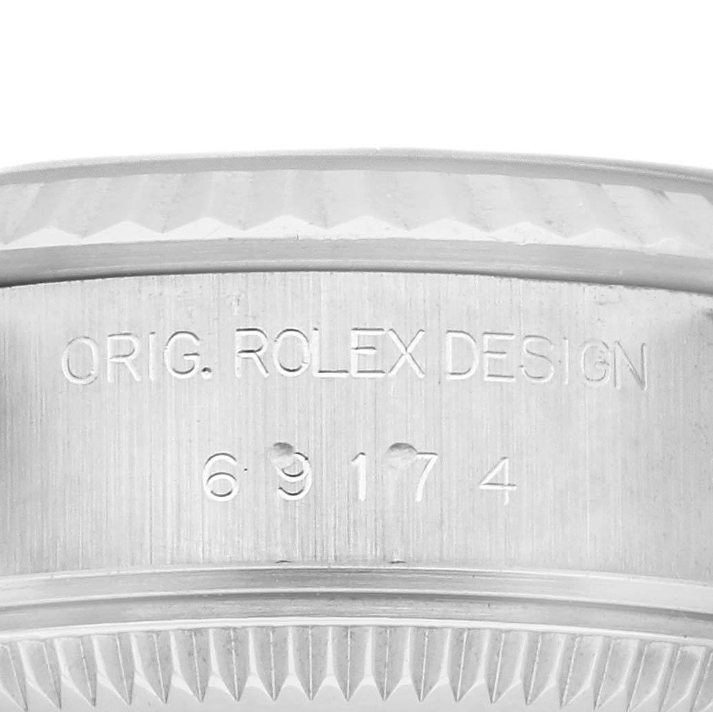 A macro shot shows the engraved serial number and "ORIG ROLEX DESIGN" on the side of a Rolex Datejust 69174 Women's Stainless Steel Pink Dial 69174 Women's Stainless Steel Pink Dial watch case.