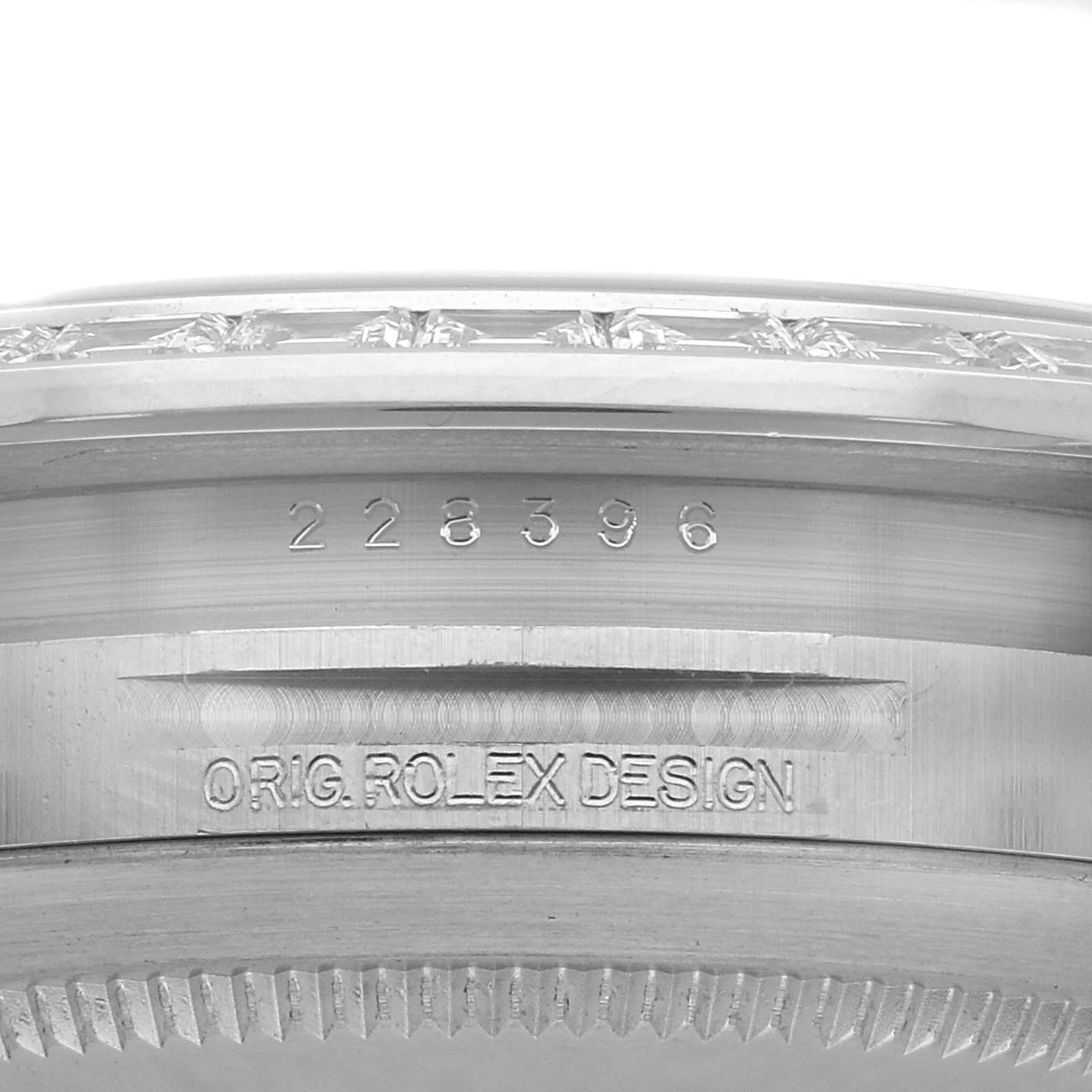 The image shows a close-up of the side of a Rolex President 228396 Men
s Platinum Silver Dial model case, featuring engraved numbers and "ORIG. ROLEX DESIGN."