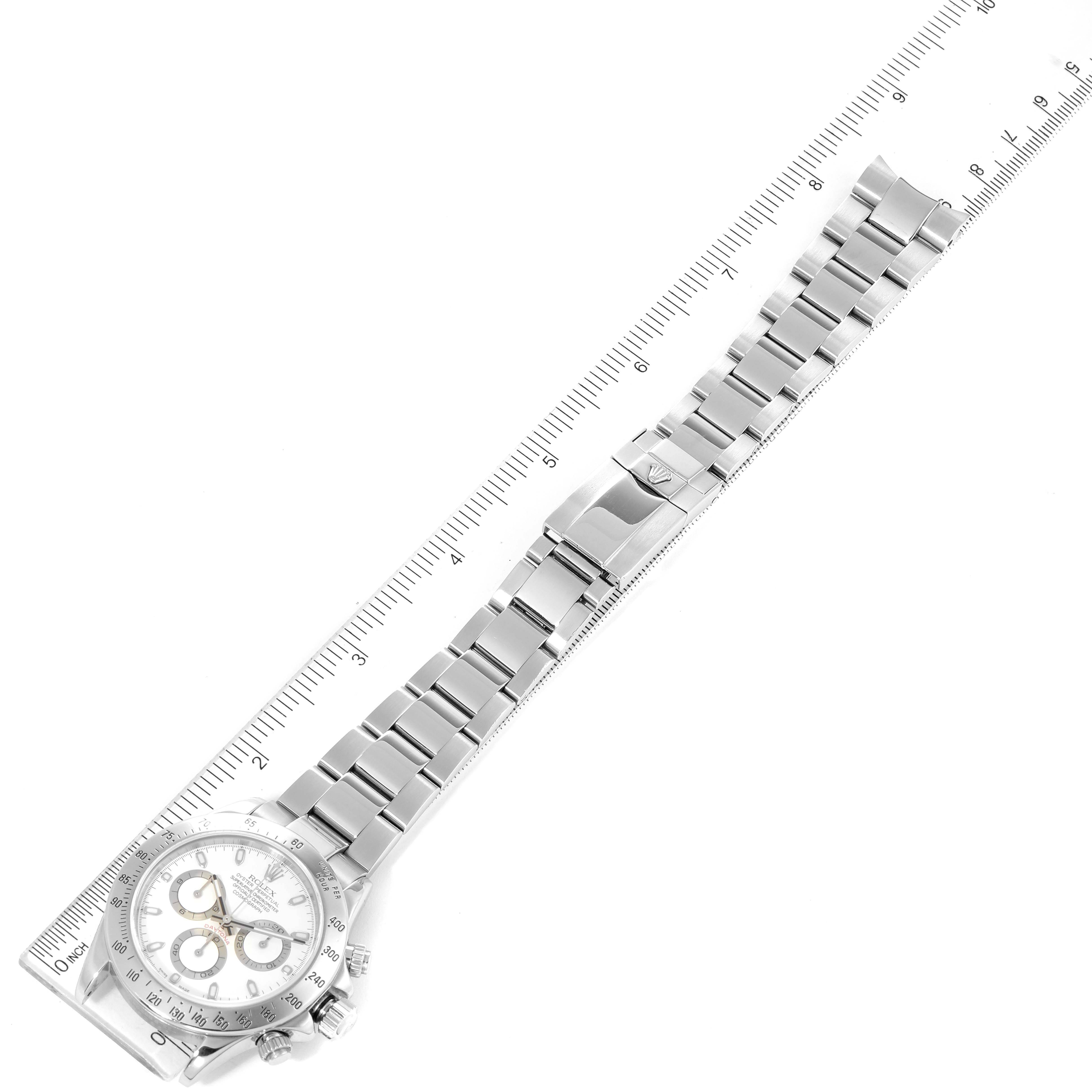 The image shows a Rolex Daytona 116520 Men's Stainless Steel White Dial 116520 Men's Stainless Steel White Dial watch laid flat with its full bracelet and clasp visible, alongside a ruler for scale.