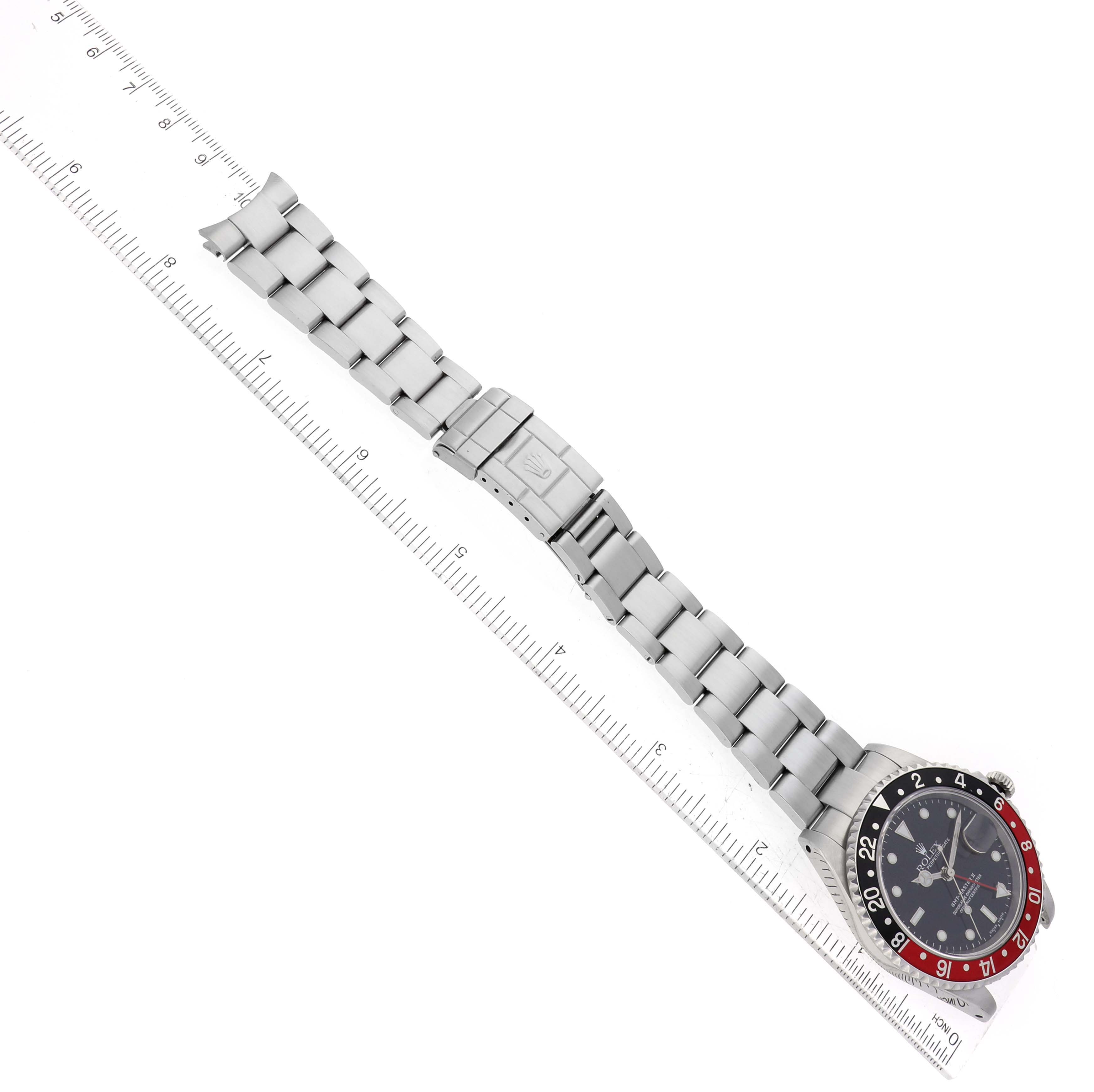 This image shows a Rolex GMT-Master 16710 Men
s Stainless Steel Black Dial 16710 Men
s Stainless Steel Black Dial watch laid flat next to a ruler, displaying the entire bracelet and clasp from an overhead angle.
