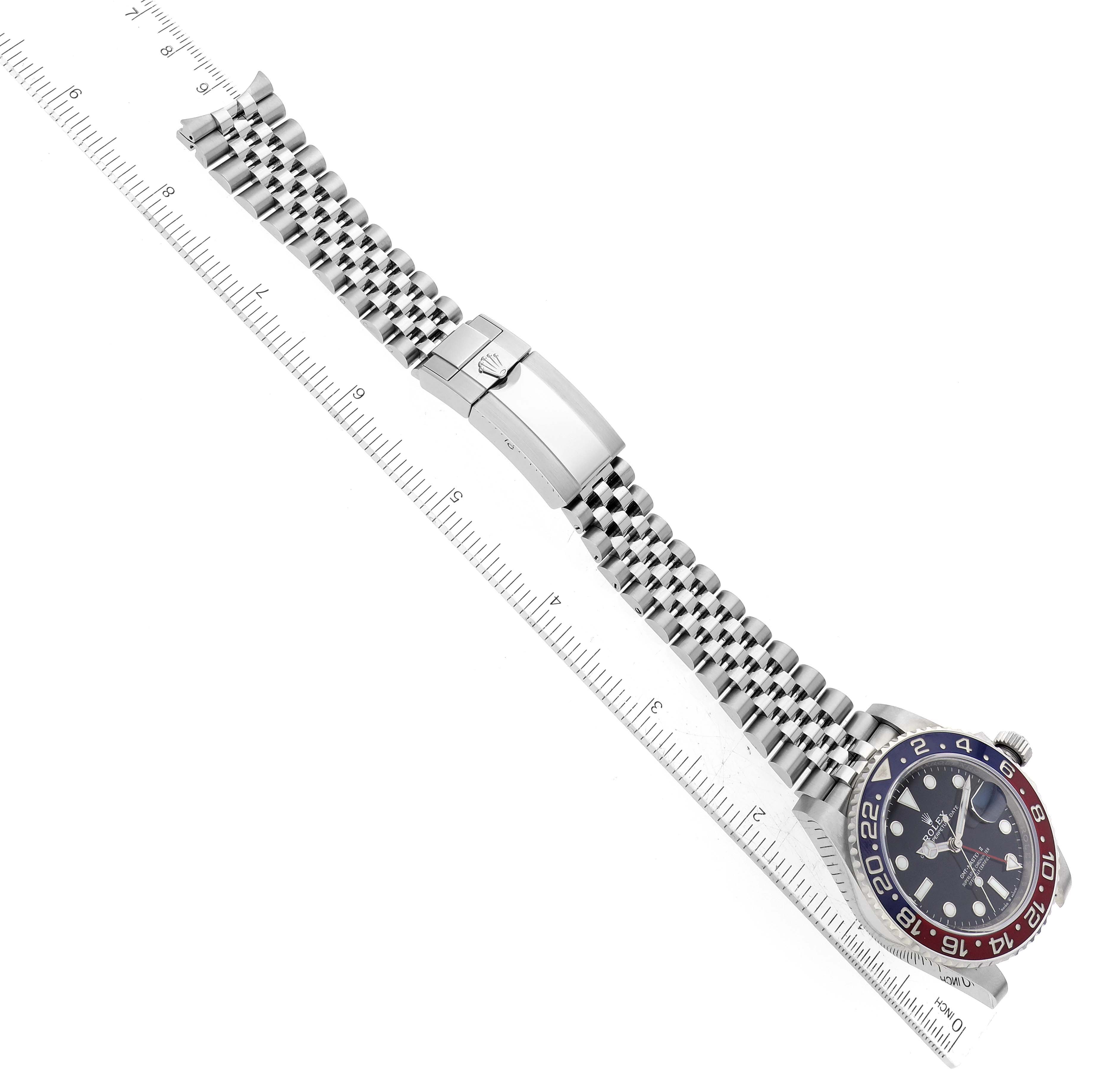 The Rolex GMT-Master 126710BLRO Men's Stainless Steel Black Dial 126710BLRO Men's Stainless Steel Black Dial watch is shown from an overhead angle, displaying the bracelet, clasp, and bezel with a ruler for scale.