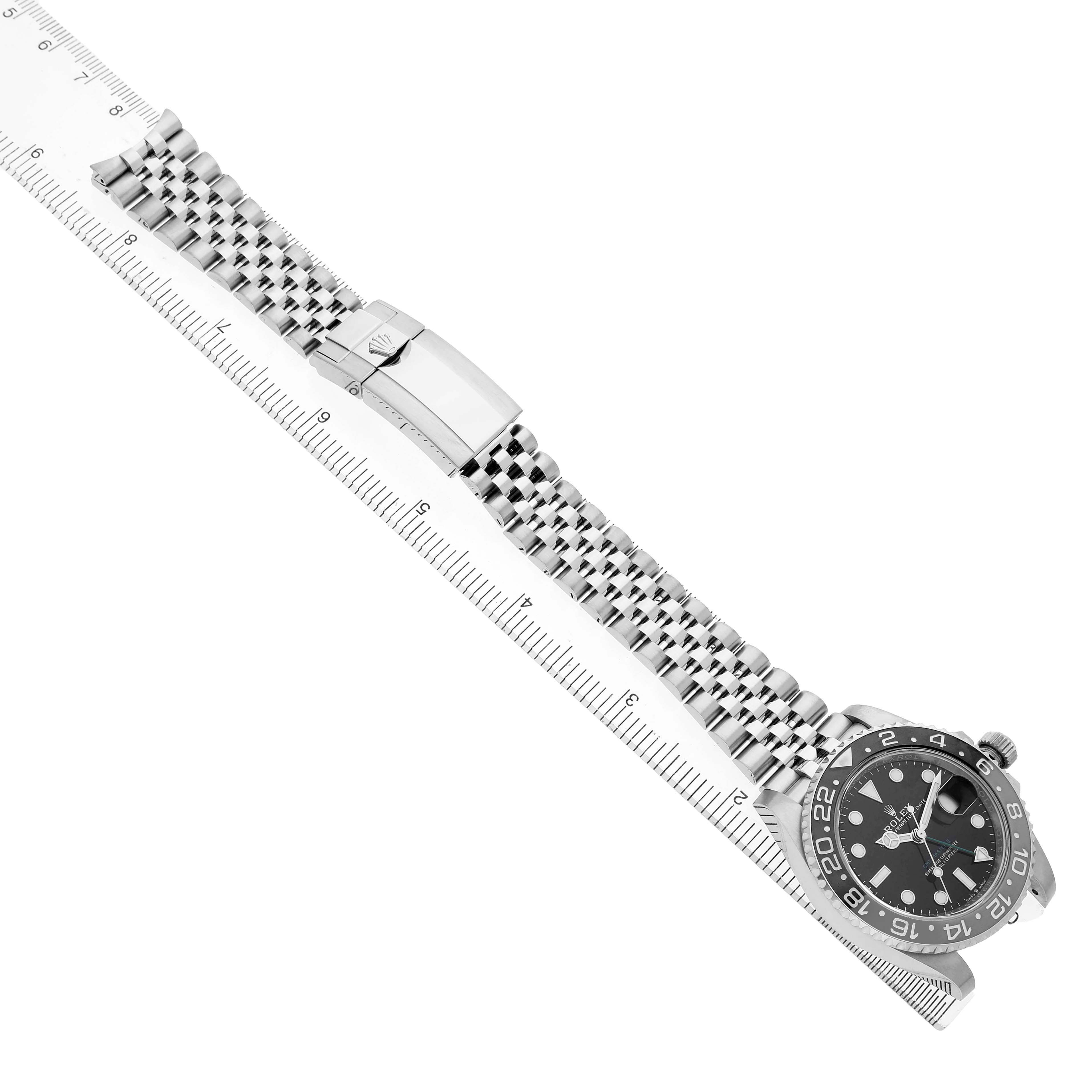 The Rolex GMT-Master 126710 Men's Stainless Steel Black Dial watch is shown from a side angle, highlighting its face, bezel, bracelet, and clasp alongside a ruler.