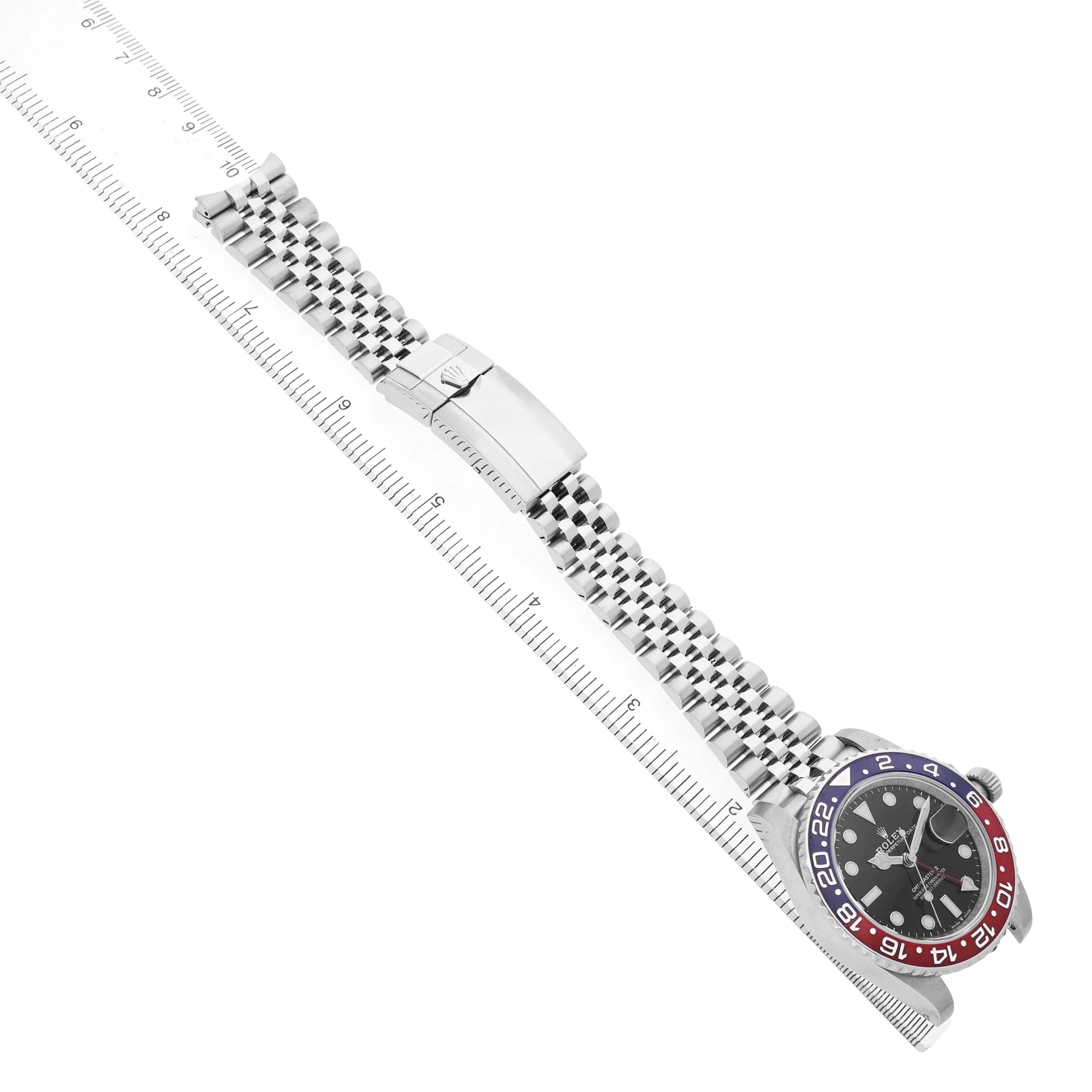 The Rolex GMT-Master 126710BLRO Men's Stainless Steel Black Dial watch is shown in an angled view, highlighting the bezel, face, and bracelet alongside a ruler for scale.