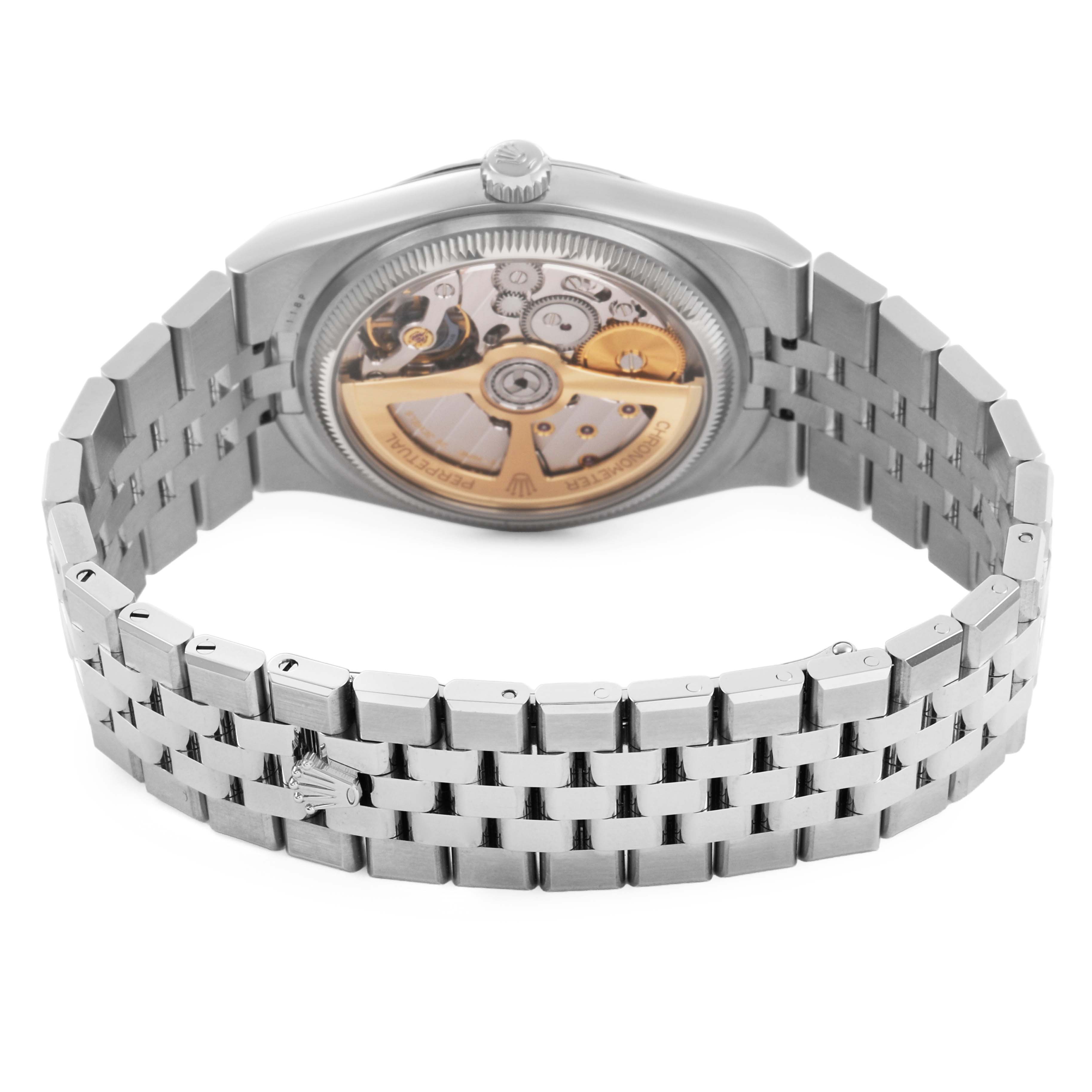 The Land-Dweller by Rolex is shown from the back, displaying its case back and movement, with the bracelet partially visible.