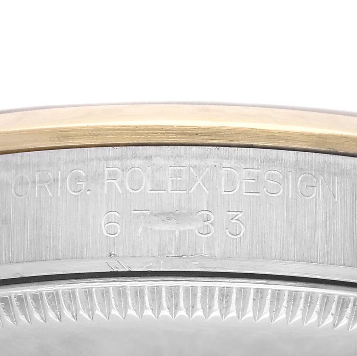 This image shows a close-up of the engraved bezel of a Rolex Mid-Size 67483 Women's Steel and Gold (two tone) Grey Dial 67483 Women's Steel and Gold (two tone) Grey Dial model, displaying the "ORIG. ROLEX DESIGN" text and part of the serial number.