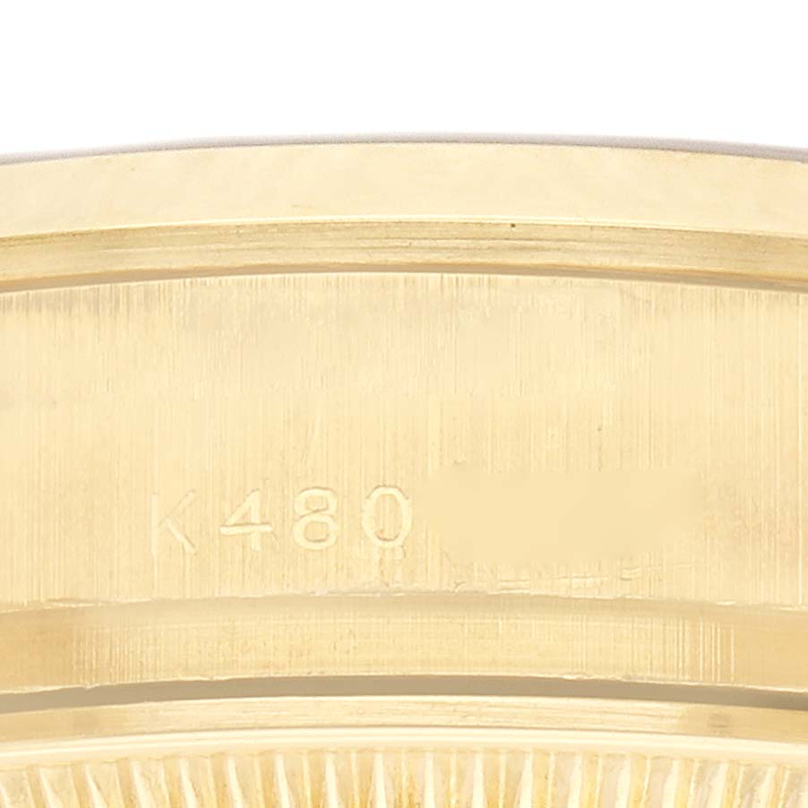 The image shows a close-up of the side view of a Rolex President 179168 Men
s Yellow Gold White Dial watch
s gold bezel with engraved markings.