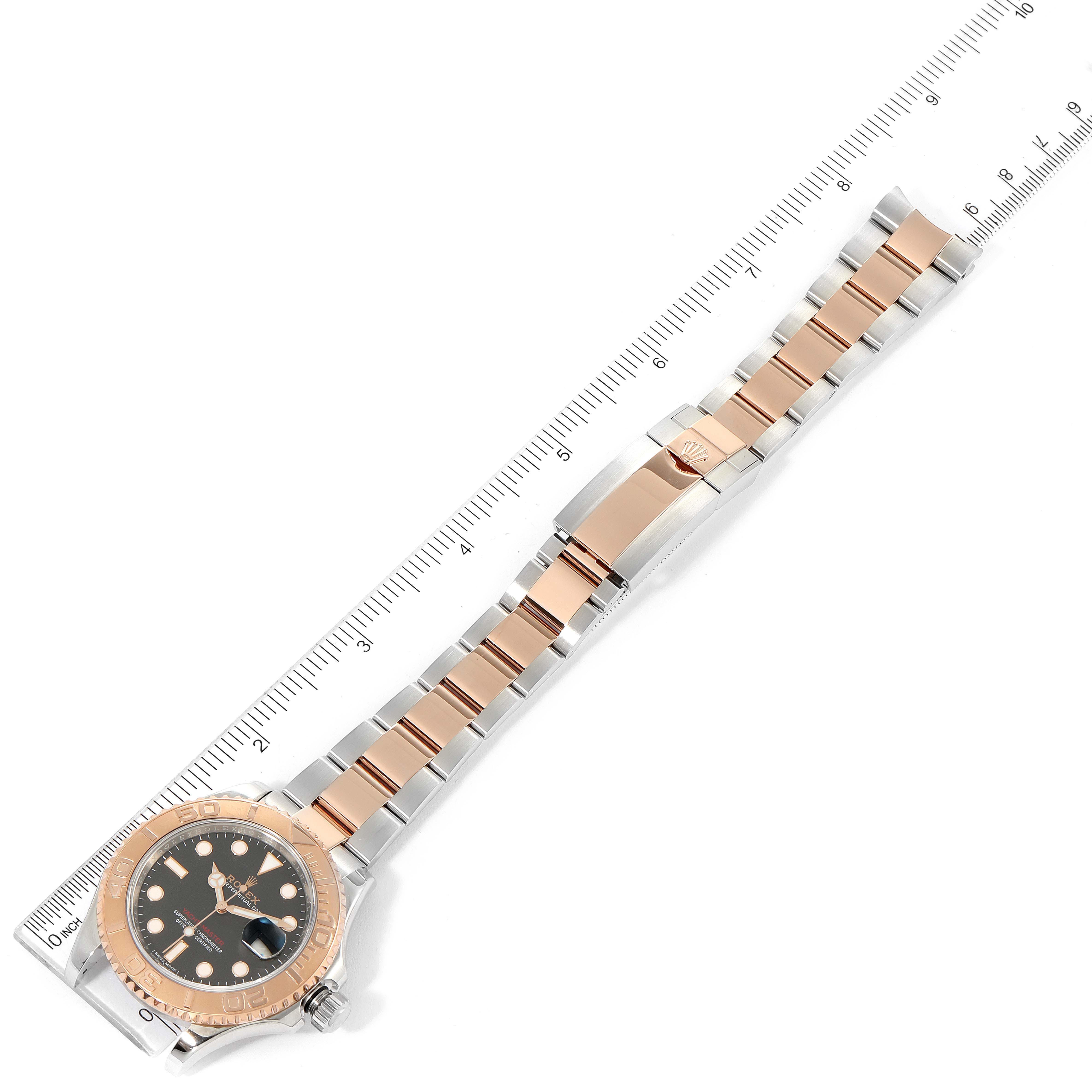 The Rolex Yacht-Master 116621 Men's Steel and Gold (two tone) Black Dial 116621 Men's Steel and Gold (two tone) Black Dial watch is shown from a top-down angle, displaying its face, bezel, and two-tone bracelet with a ruler for scale.