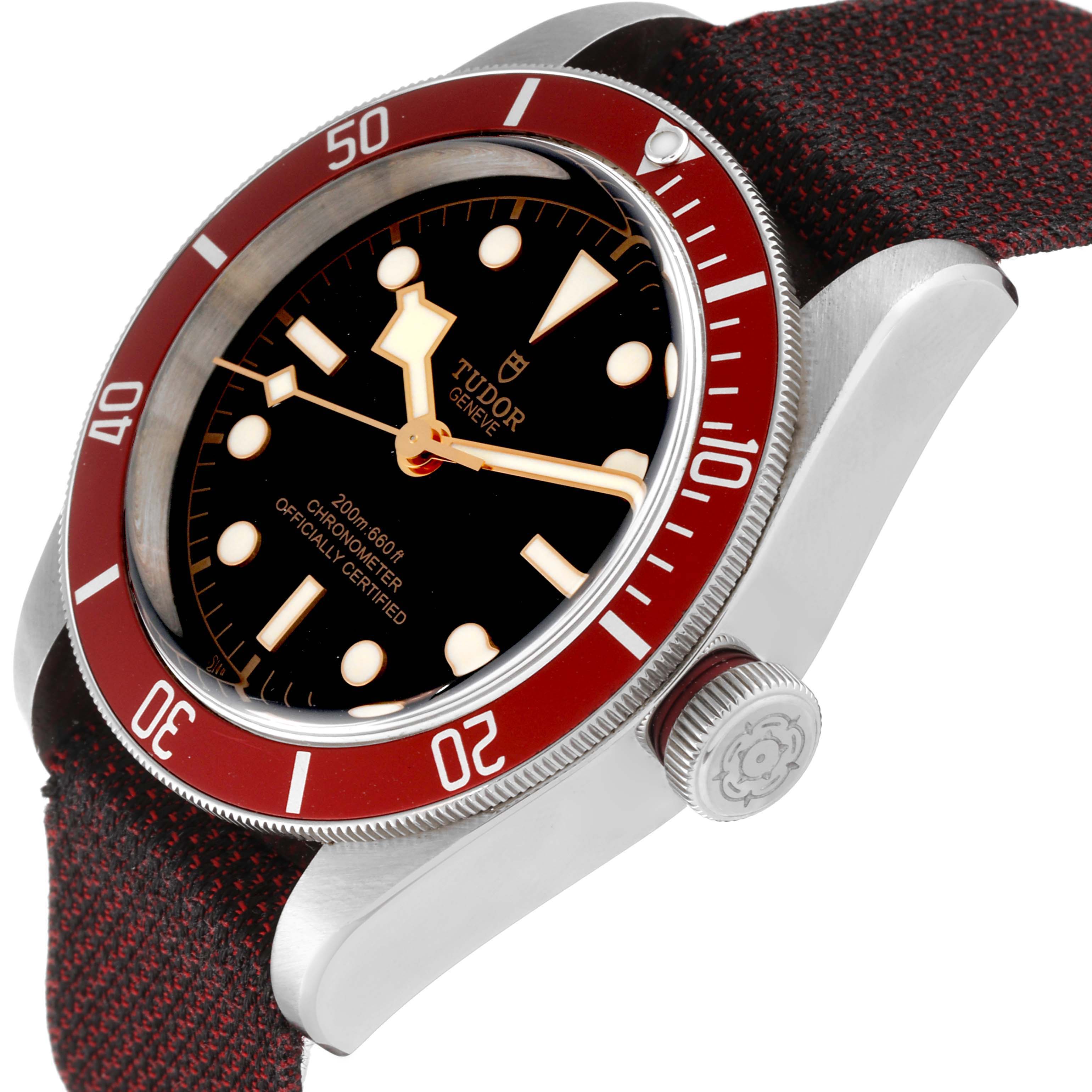 The image shows a Tudor Heritage Black Bay 79230R Men's Stainless Steel Black Dial 79230R Men's Stainless Steel Black Dial watch at a three-quarter angle, displaying the dial, red bezel, crown, and fabric strap.