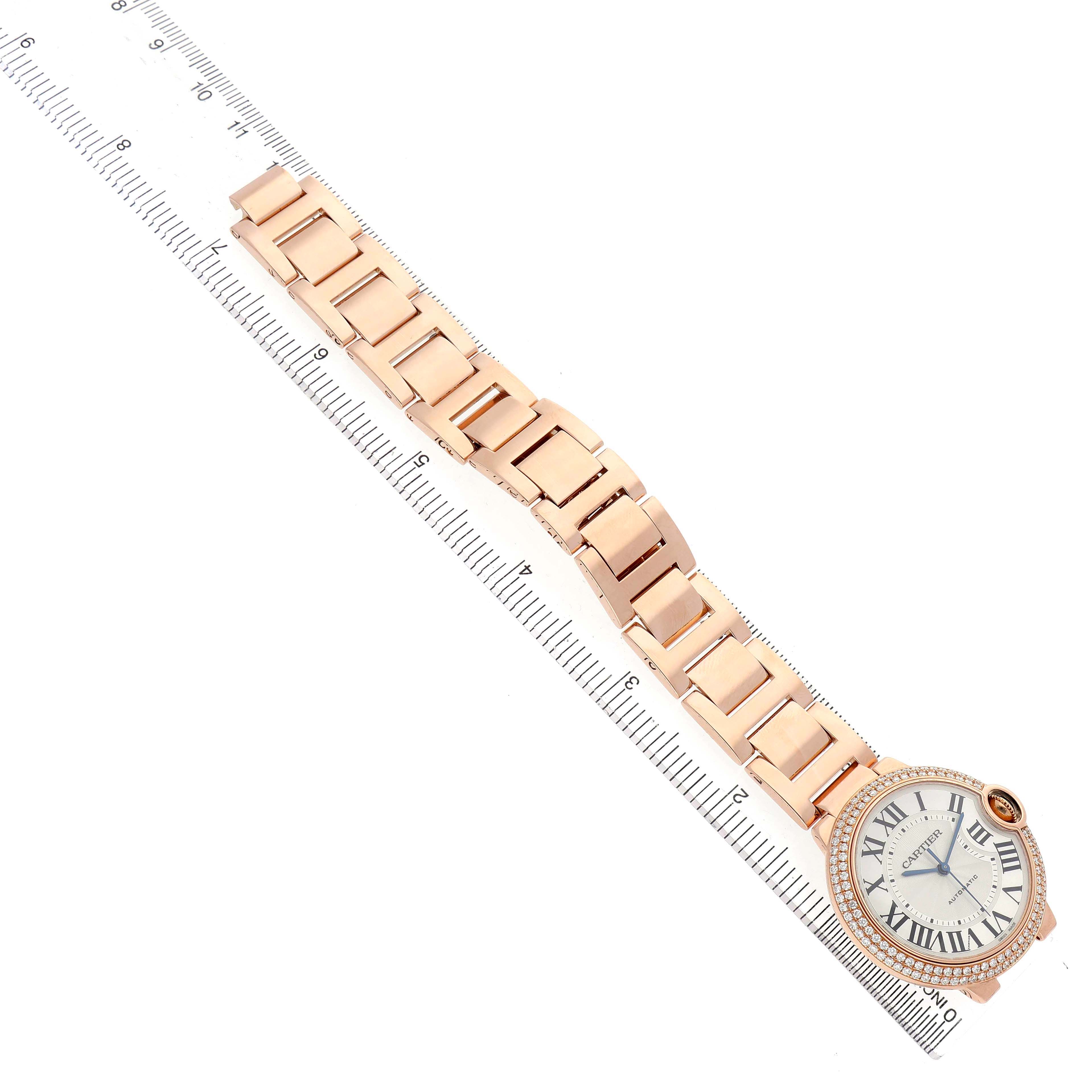 The image shows an overhead view of a Cartier Ballon Bleu WE9005Z3 Women's Rose Gold Silver Dial watch, highlighting the bracelet and face alongside a ruler.