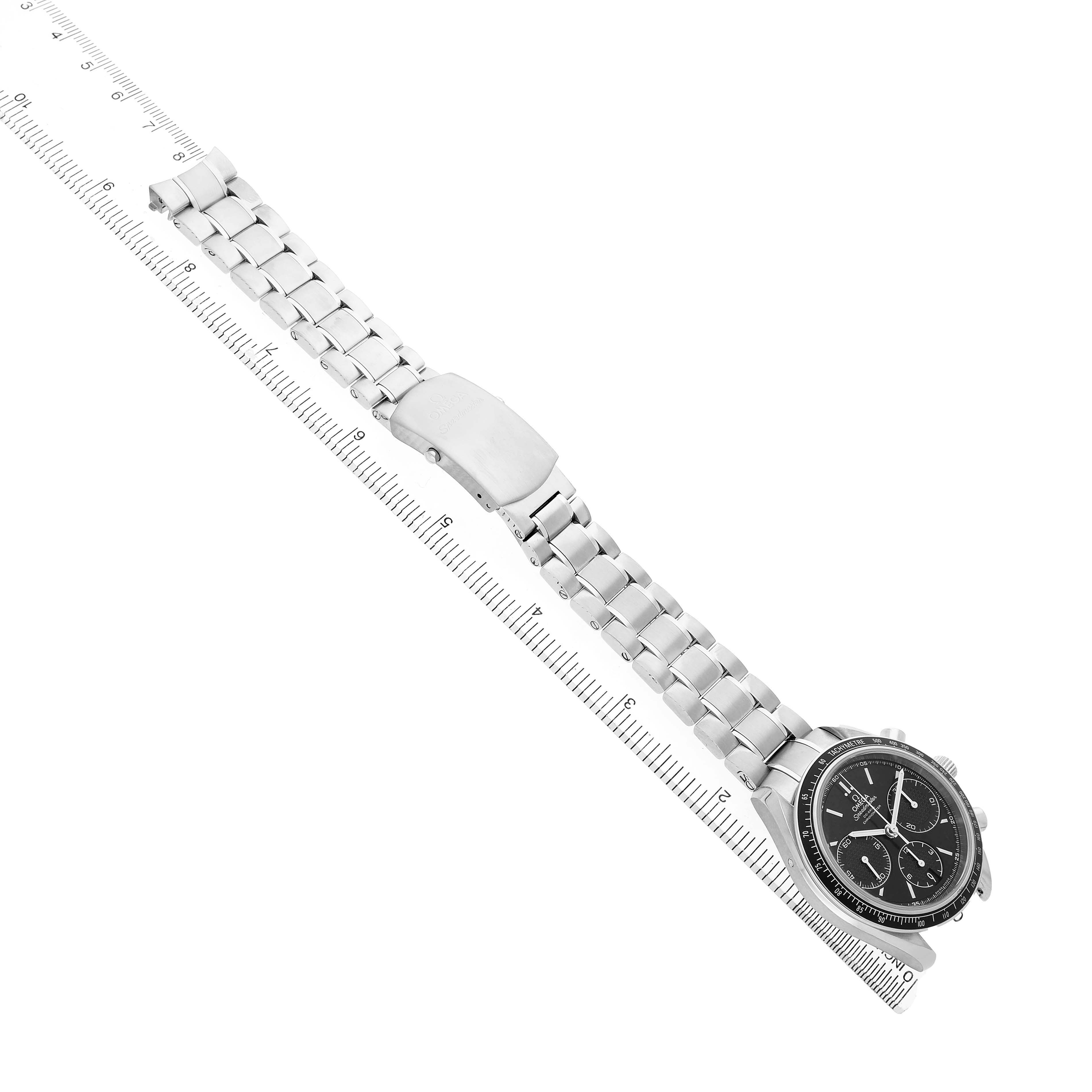 The Omega Speedmaster 326.30.40.50.01.001 Men's Stainless Steel Black Dial watch is shown from a top-down angle, highlighting the face, bracelet, and clasp alongside a ruler for scale.