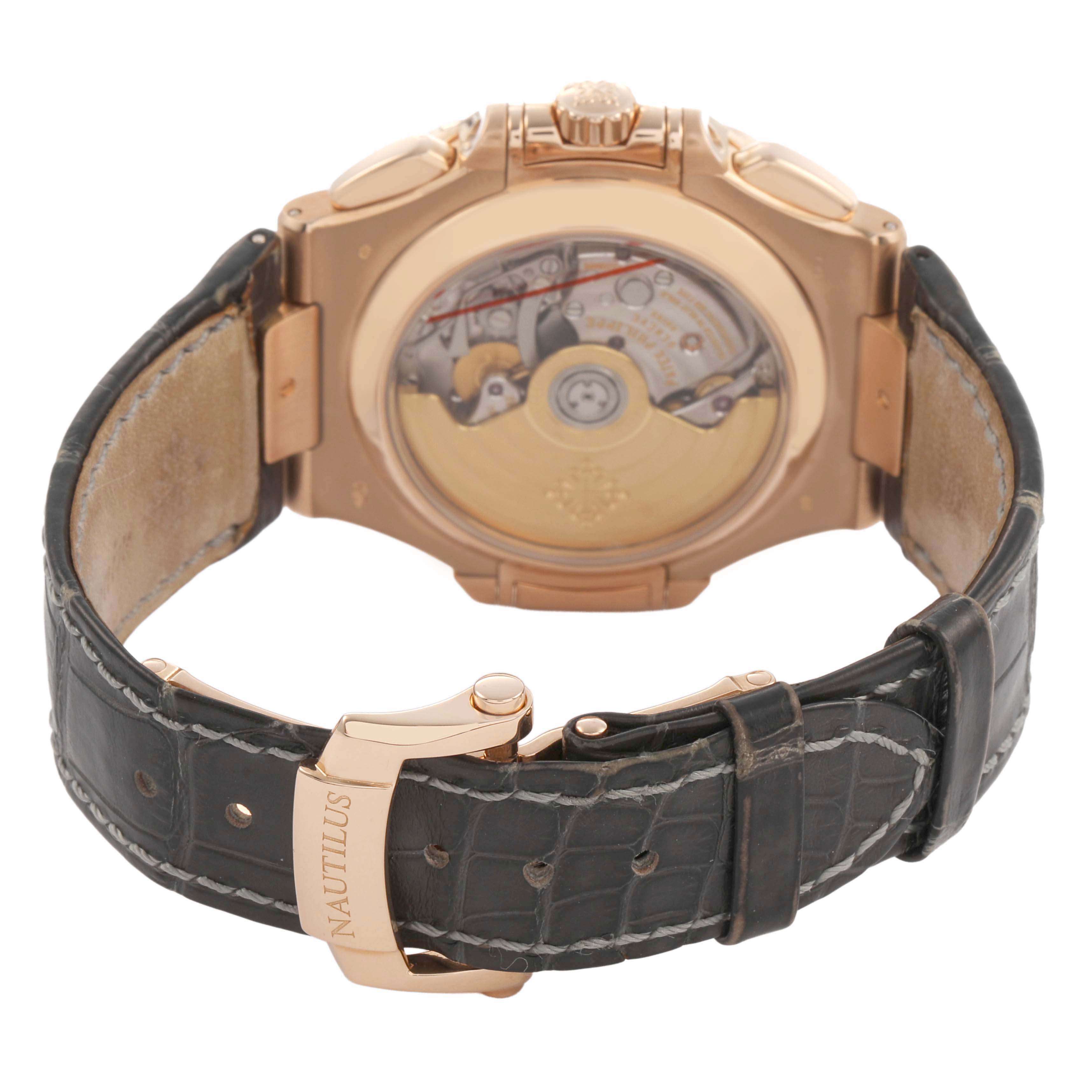 The image shows the back of a Patek Philippe Nautilus 5980R-001 Men's Rose Gold Brown Dial, displaying the movement and leather band with "Nautilus" branding on the clasp.