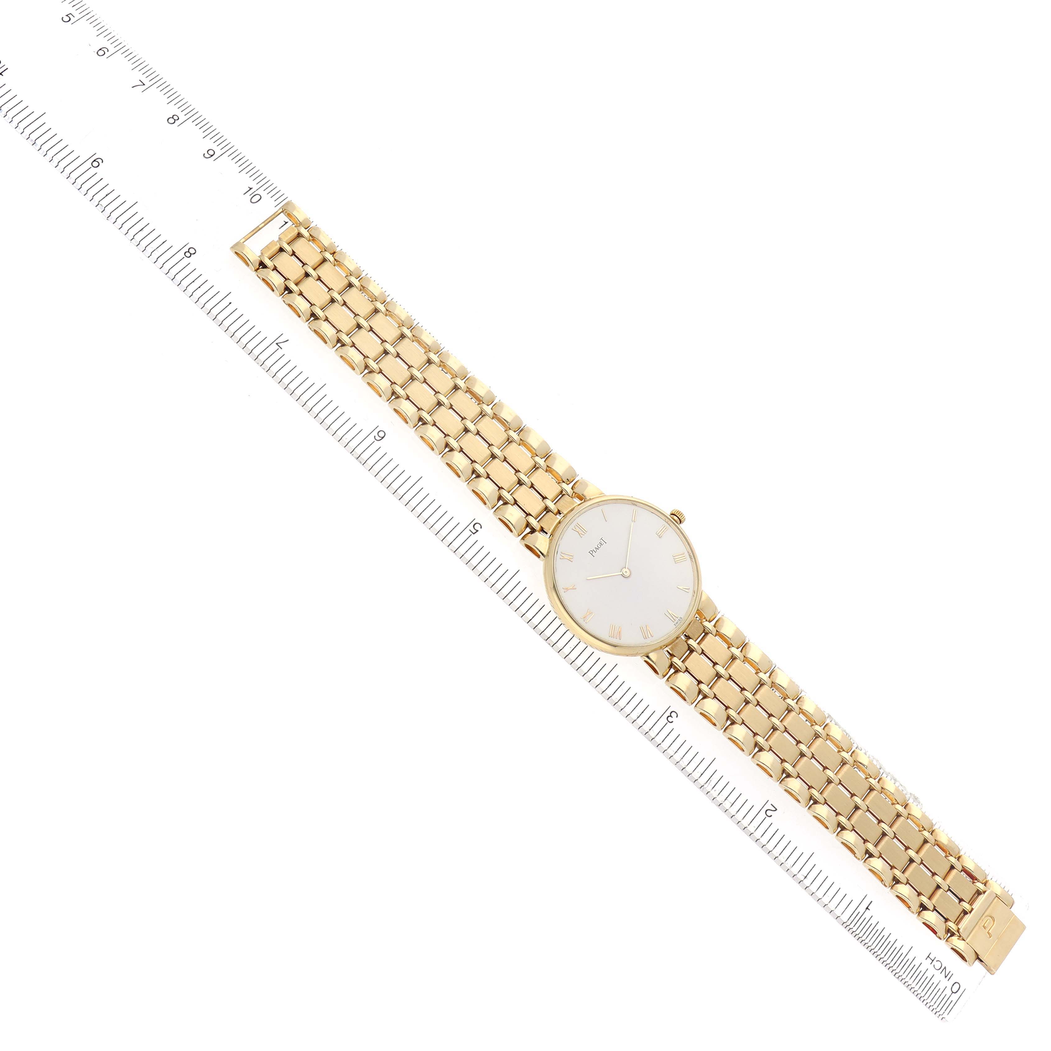The Piaget 8065K43 Women
s Yellow Gold White Dial 8065K43 watch is shown from a top-down angle, displaying its gold strap and white dial alongside a ruler for scale.
