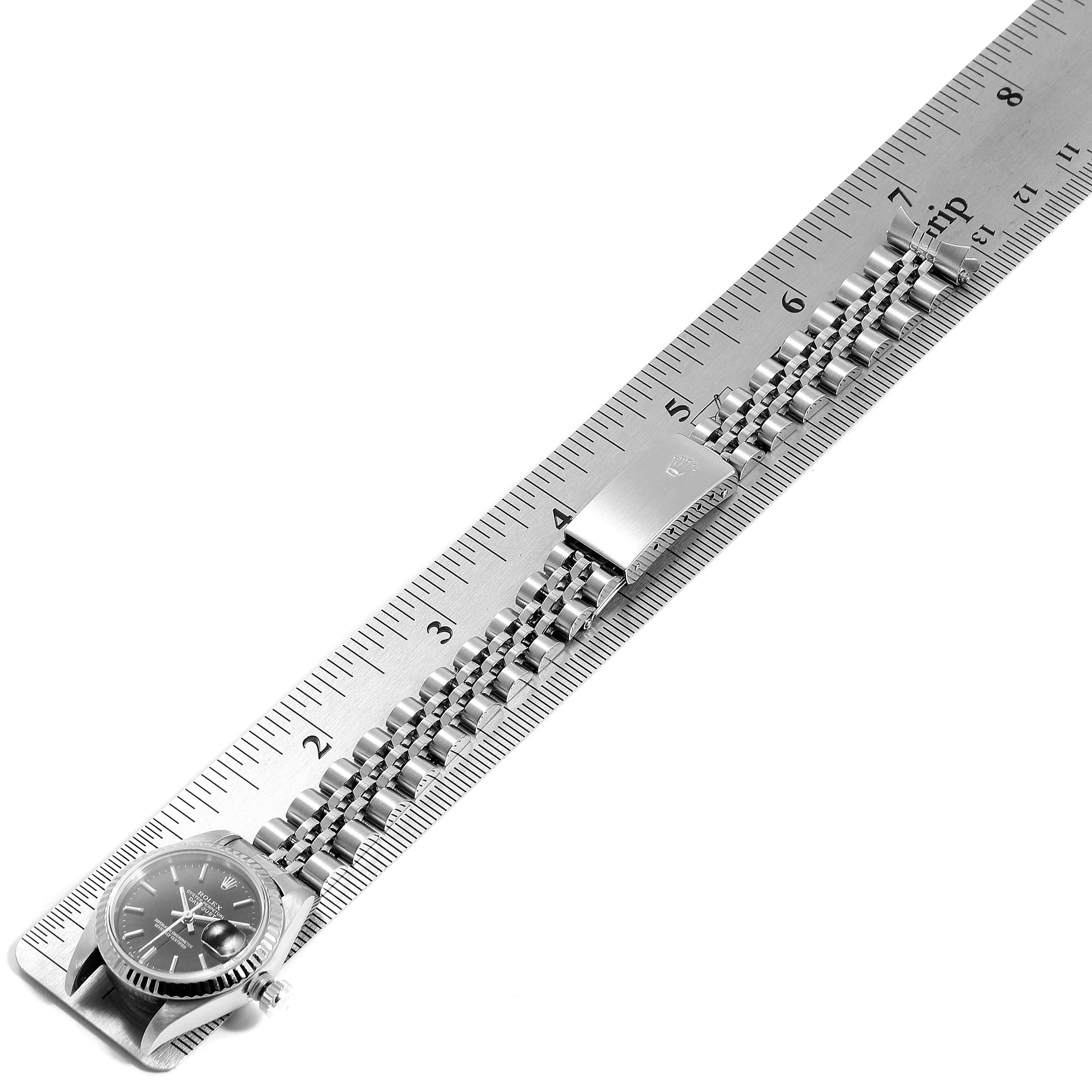 The image shows a top view of a Rolex Datejust 79174 Women's Stainless Steel Black Dial 79174 Women's Stainless Steel Black Dial watch with its bracelet measured against a metal ruler.