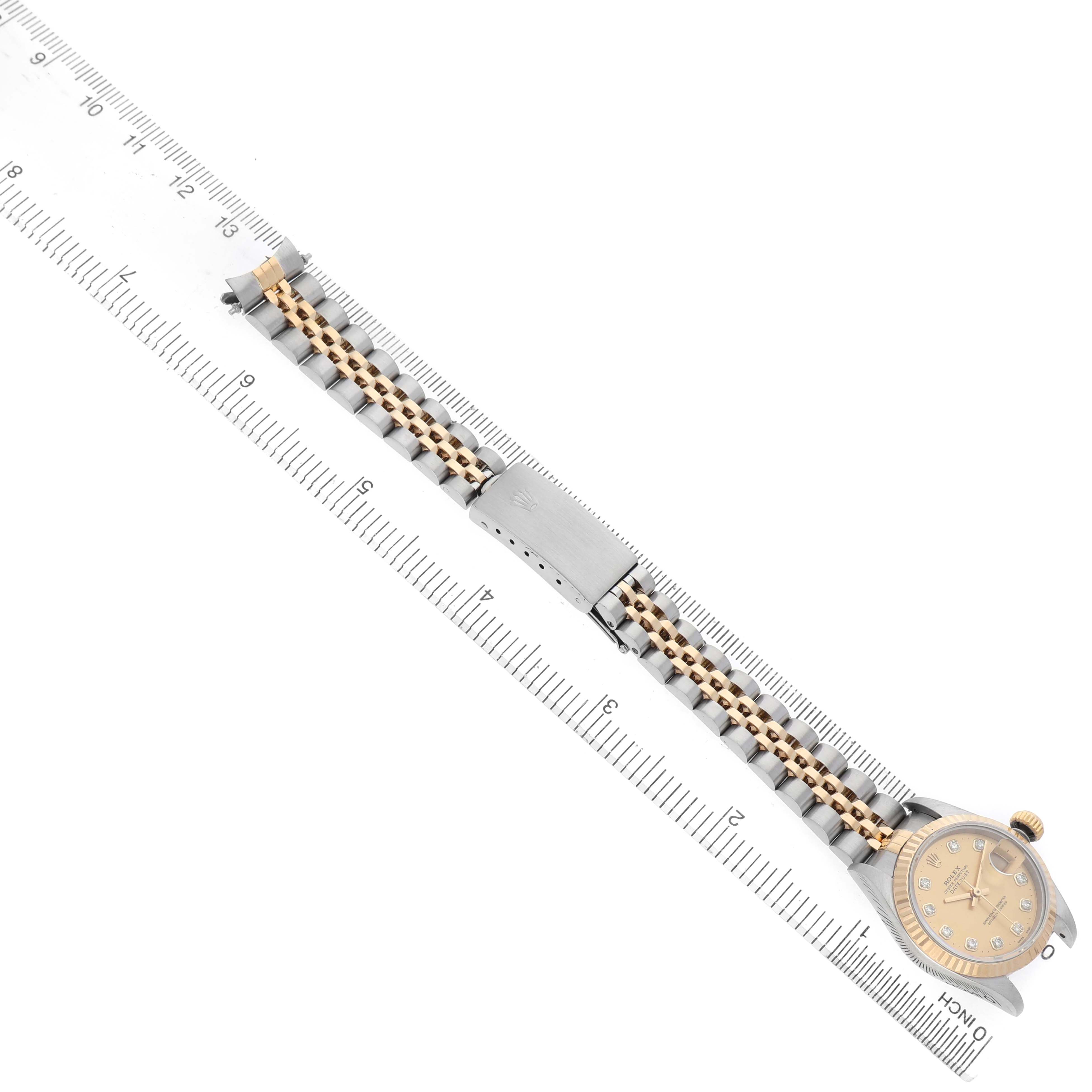 The Rolex Datejust 69173 Women's Steel and Gold (two tone) Champagne Dial watch is shown from a top-down angle, displaying the dial, bracelet, and clasp alongside a ruler.