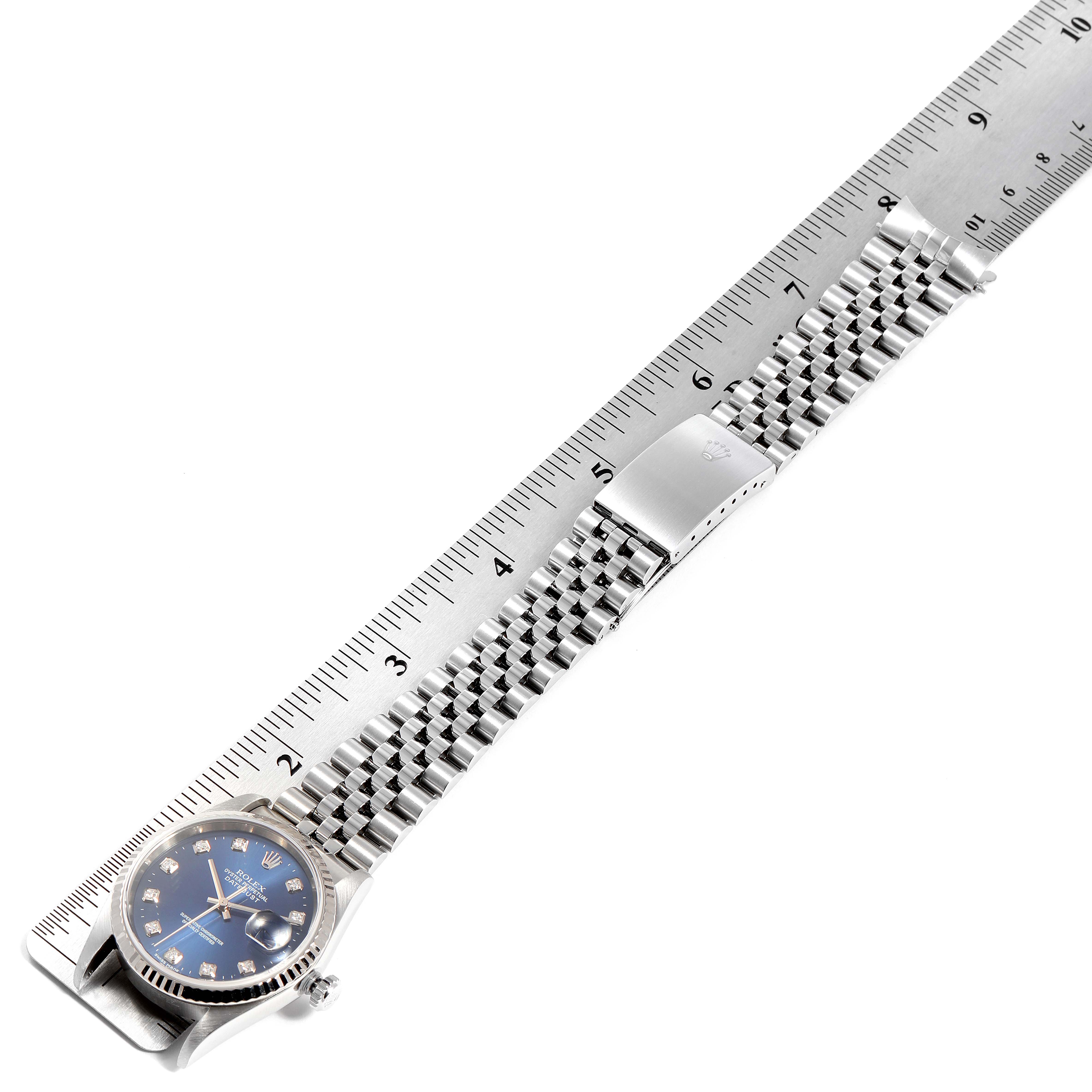 The image shows a top-down view of a Rolex Datejust 16234 Men's Stainless Steel Blue Dial 16234 Men's Stainless Steel Blue Dial watch with a jubilee bracelet and a blue dial, next to a ruler.