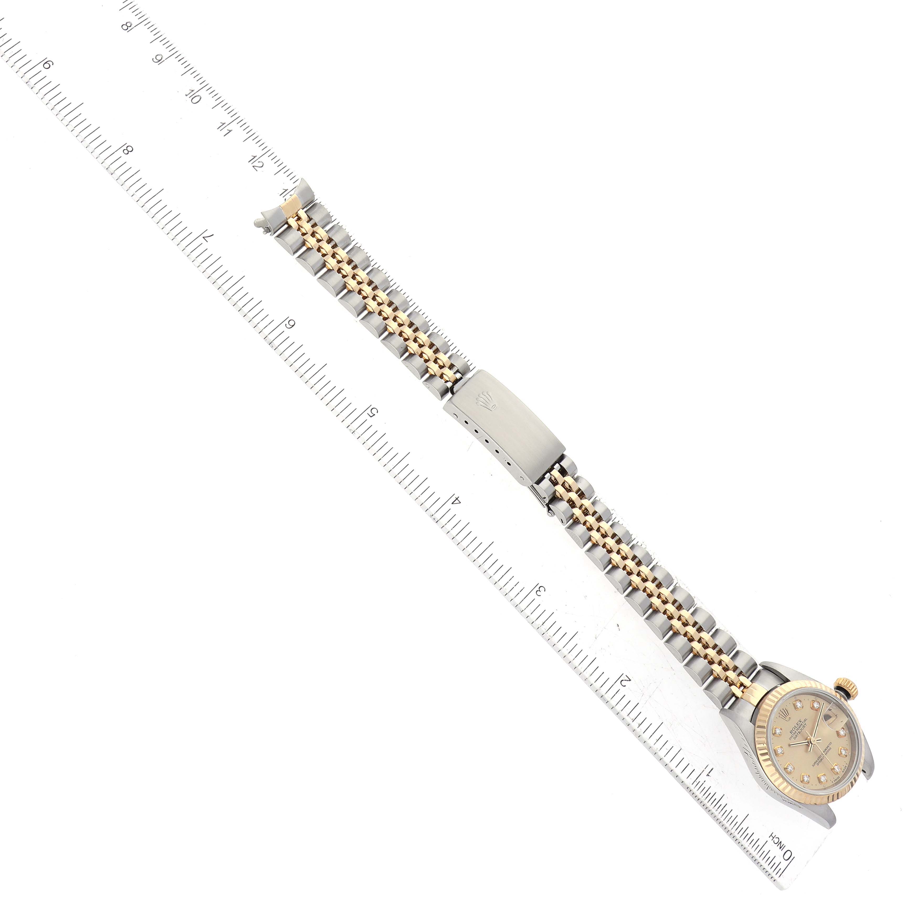 The image shows a Rolex Datejust 79173 Women's Steel and Gold (two tone) Champagne Dial 79173 Women's Steel and Gold (two tone) Champagne Dial watch laid flat next to a ruler, displaying the watch band and face from an overhead angle.