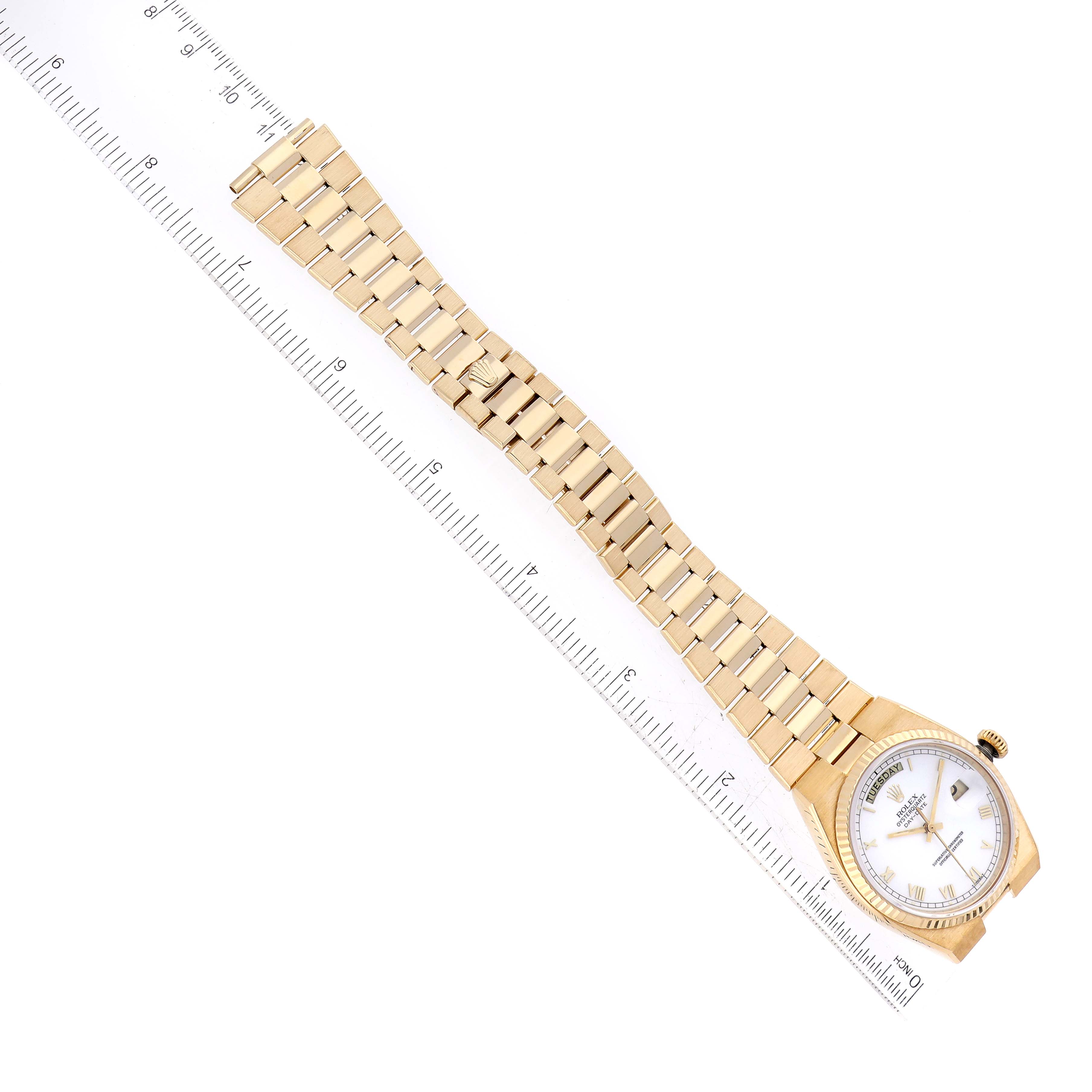 The image shows a Rolex Oysterquartz 19018 Men's Yellow Gold White Dial 19018 Men's Yellow Gold White Dial watch laid flat alongside a ruler, displaying its face, bezel, and full bracelet.