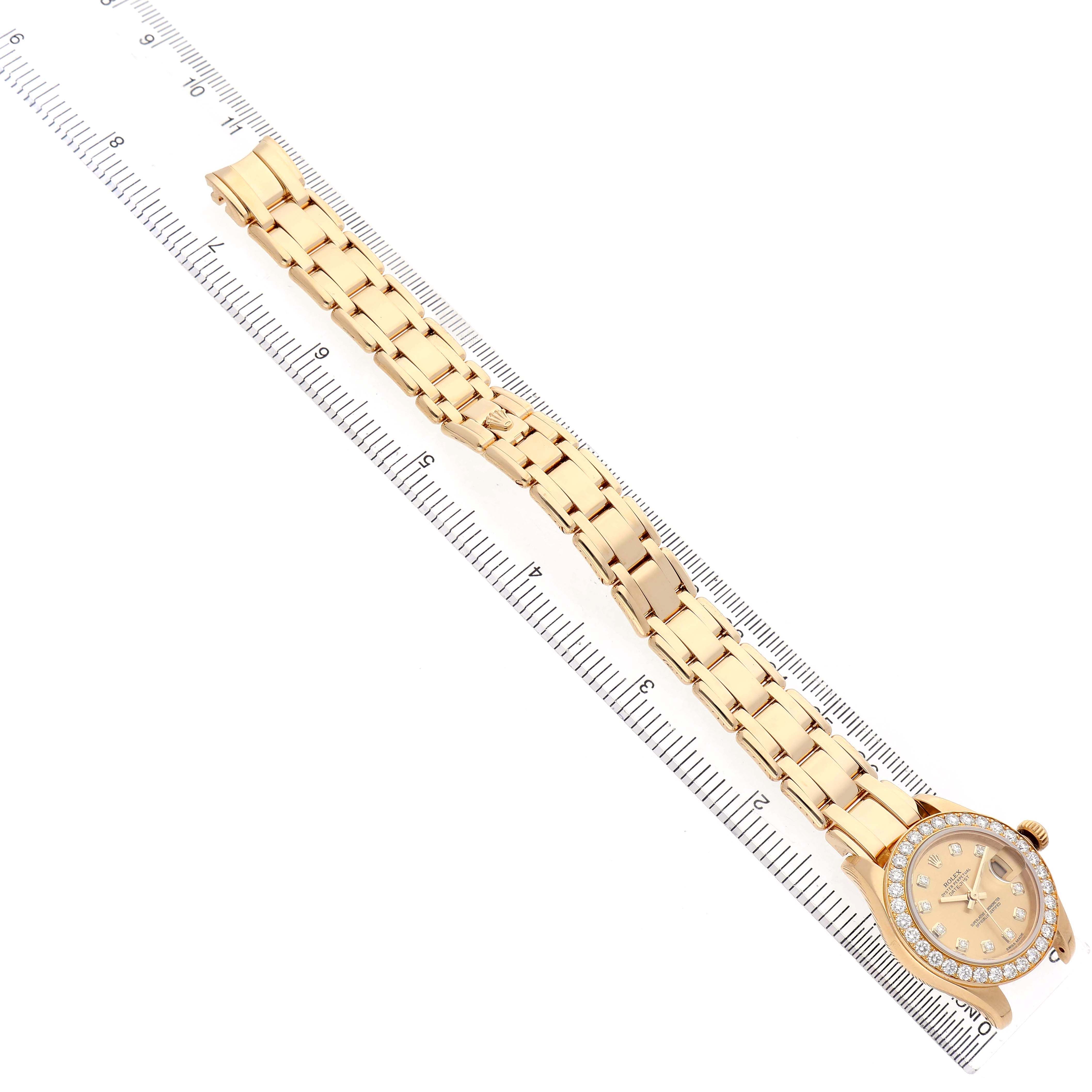 The Rolex Pearlmaster 80298 Women's Yellow Gold Champagne Dial watch is displayed from a top view, showing the entire bracelet and face alongside a ruler for scale.