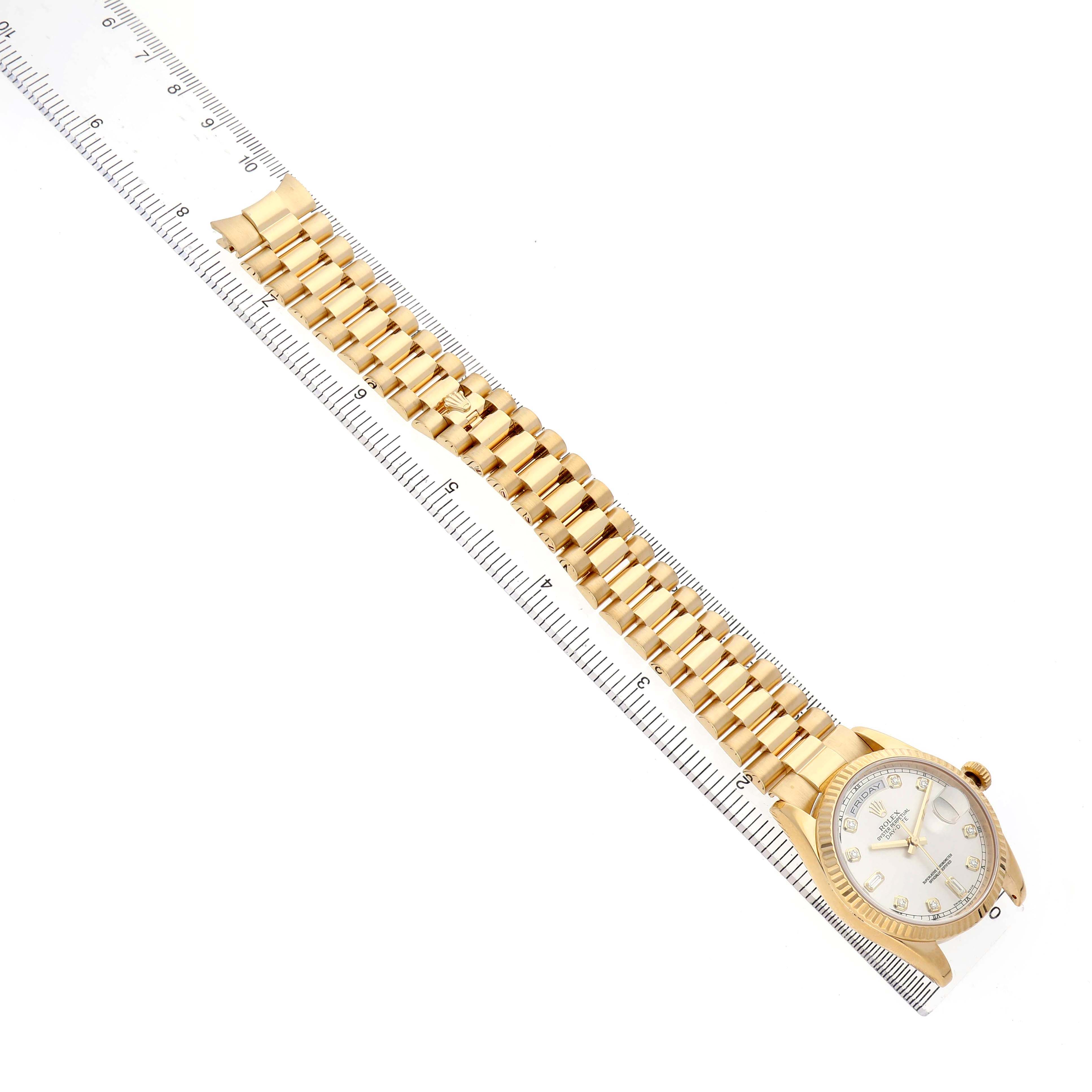 The Rolex President 118238 Men's Yellow Gold Silver Dial model watch is shown from a top-down angle, displaying the full band and face alongside a ruler.