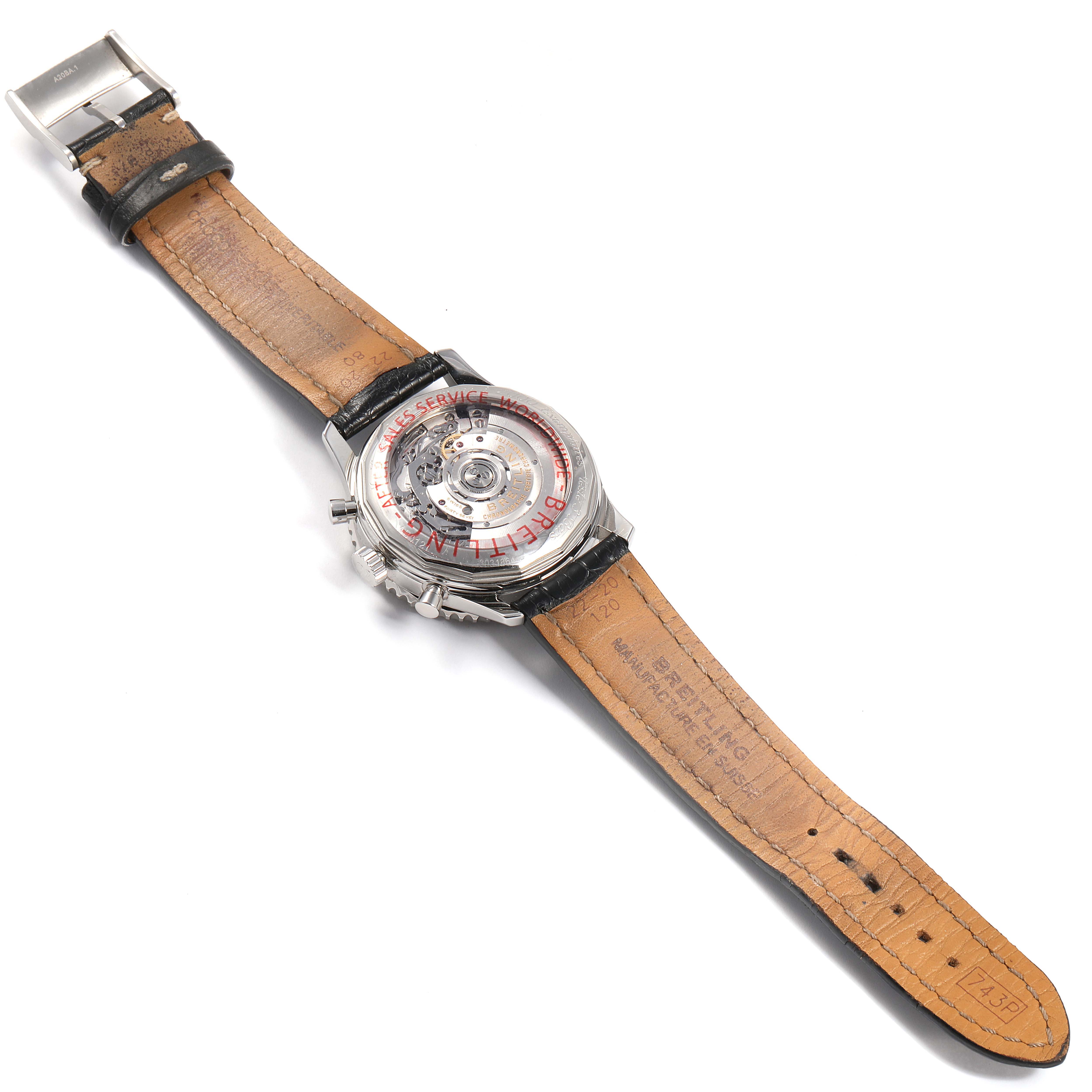 The image shows the back of a Breitling Navitimer AB0121 Men's Stainless Steel Black Dial AB0121 Men's Stainless Steel Black Dial watch and its strap, highlighting the intricate movement and leather underside.