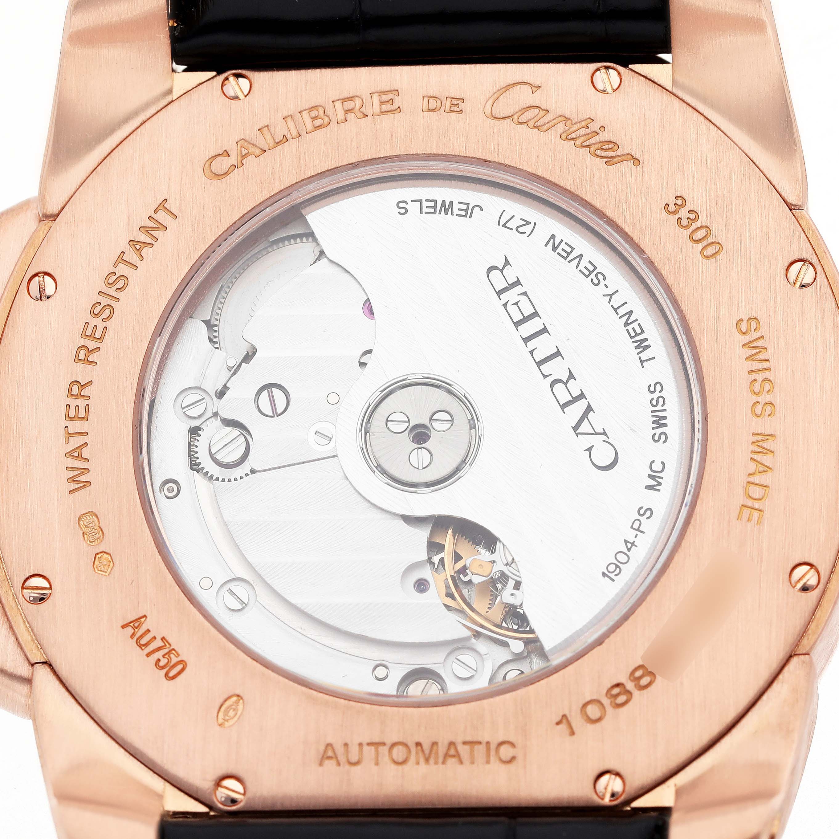 The image shows the back view of a Calibre de Cartier watch, highlighting the automatic movement and inscriptions.