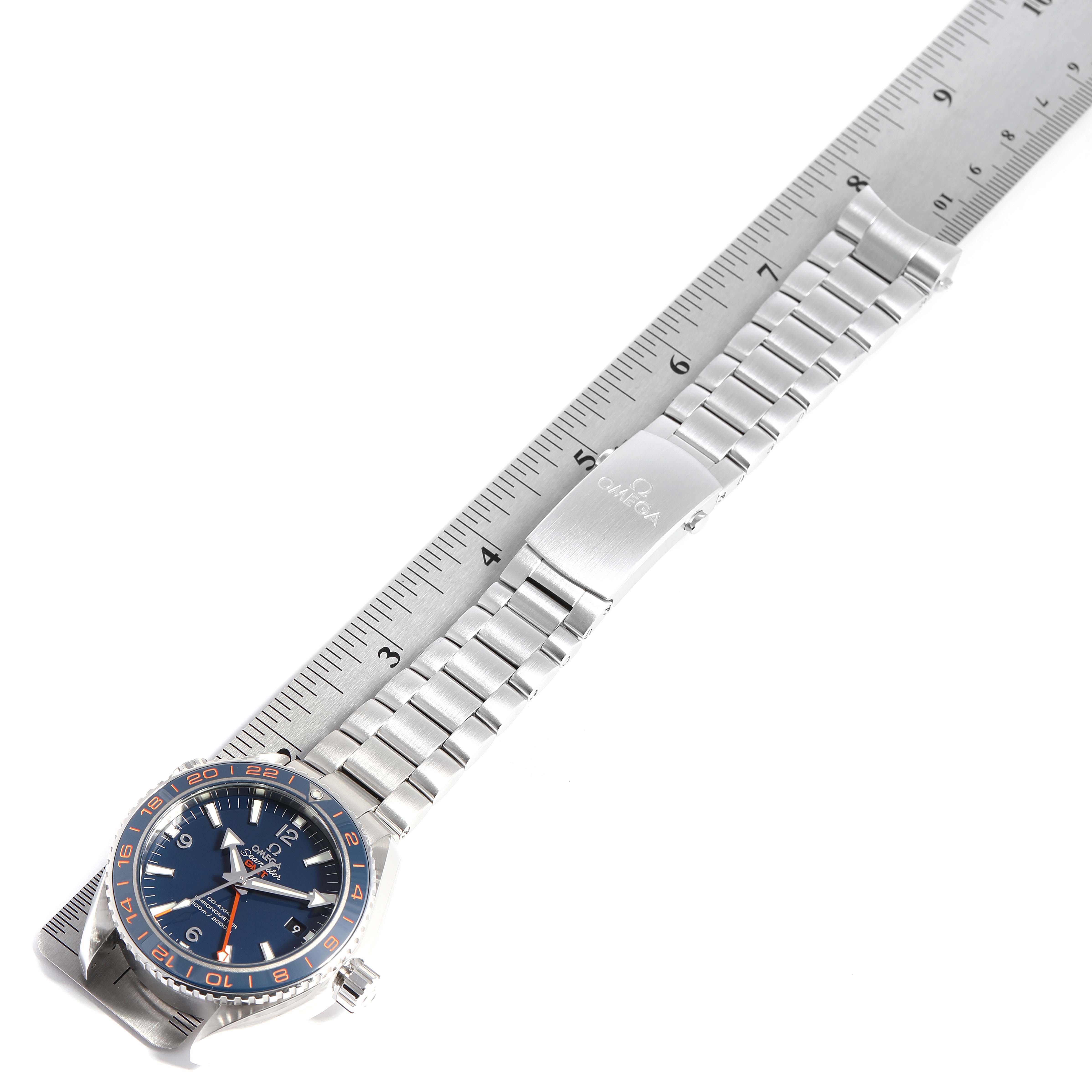 The image shows an Omega Planet Ocean 232.30.44.22.03.001 Men's Stainless Steel Blue Dial 232.30.44.22.03.001 Men's Stainless Steel Blue Dial watch laid flat with a metallic bracelet alongside a ruler for size reference.