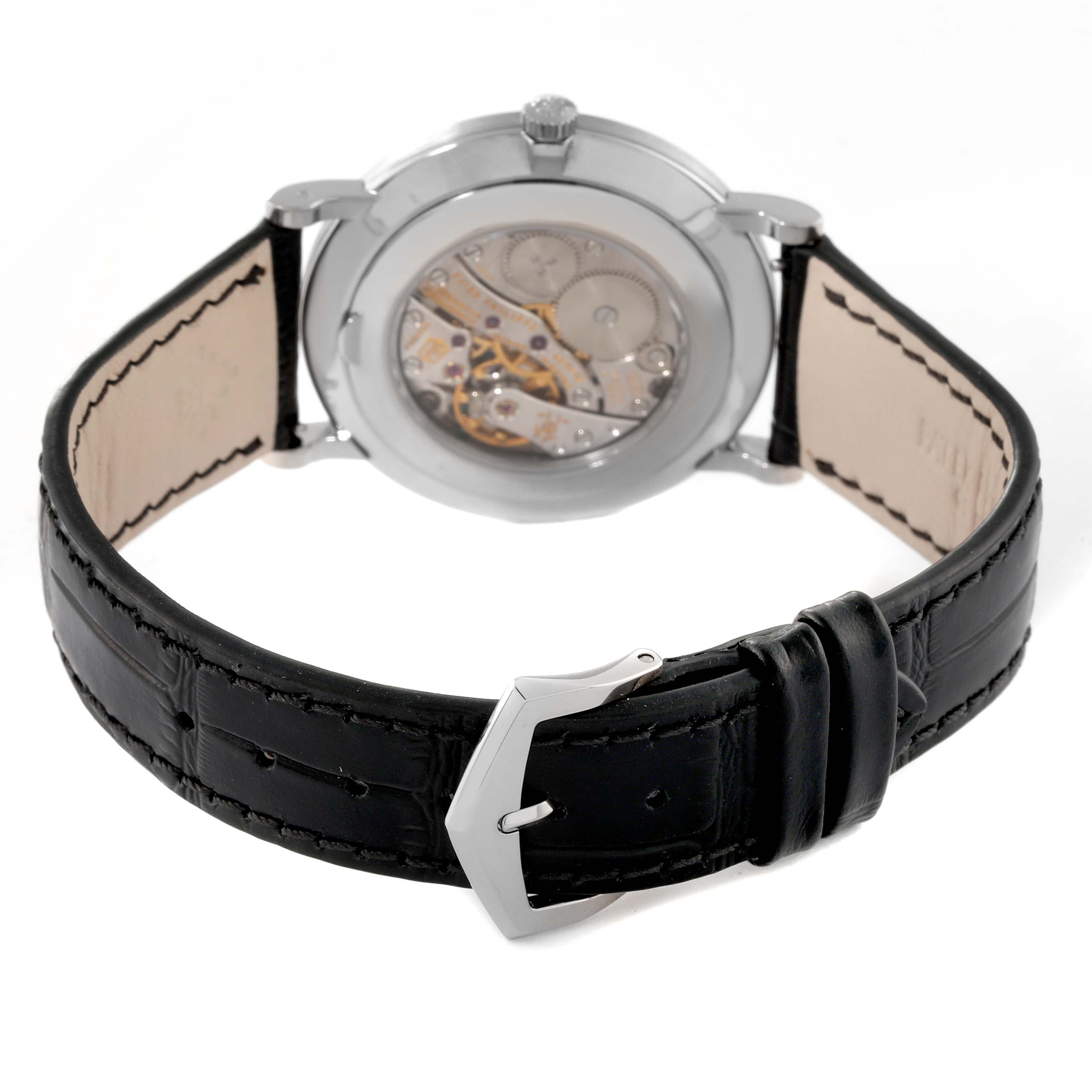 The image shows the back of a Calatrava model by Patek Philippe, highlighting the movement and black leather strap.