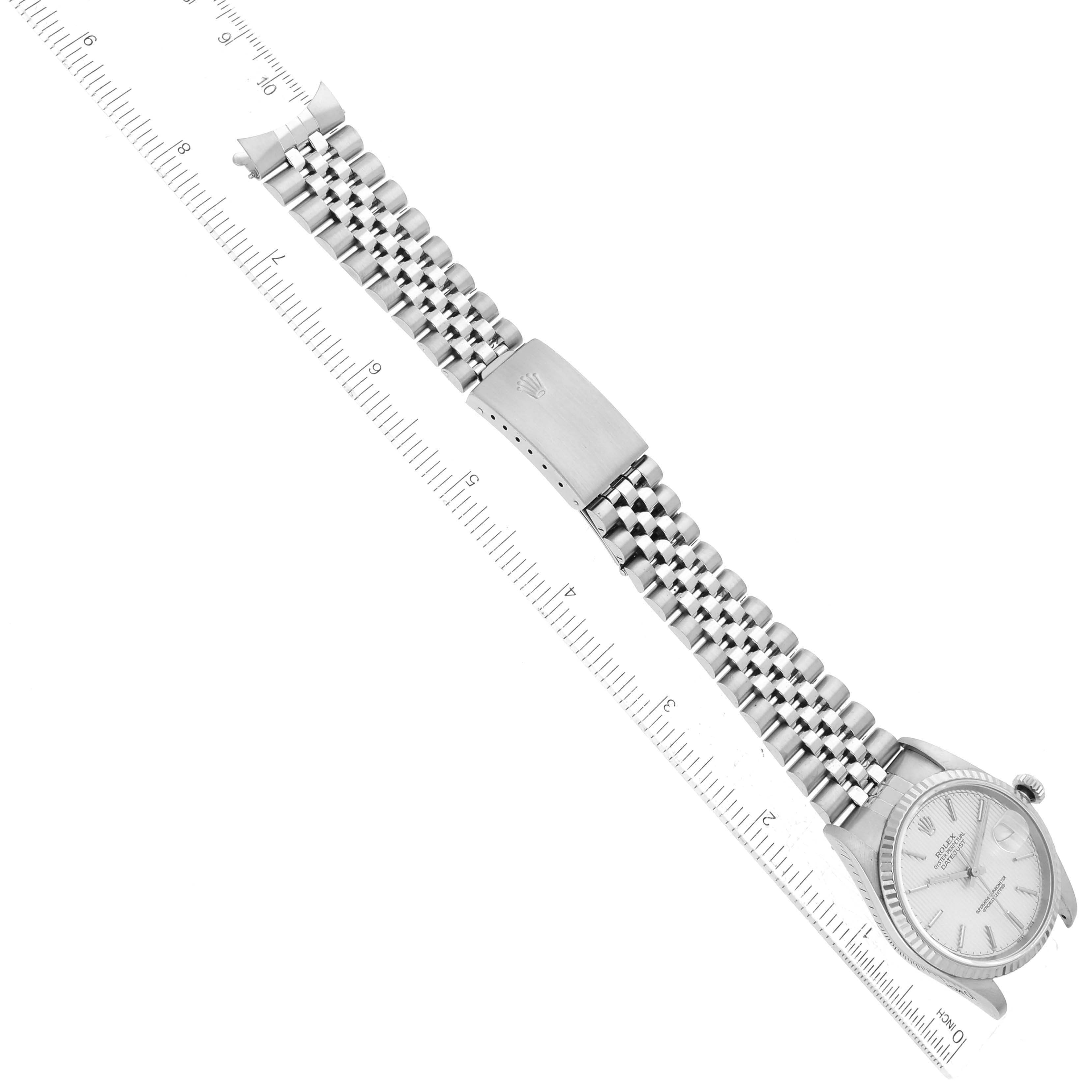 The image shows a Rolex Datejust 16234 Men's Stainless Steel Silver Dial 16234 Men's Stainless Steel Silver Dial watch from an aerial view including the face, bracelet, and clasp, next to a ruler for scale.