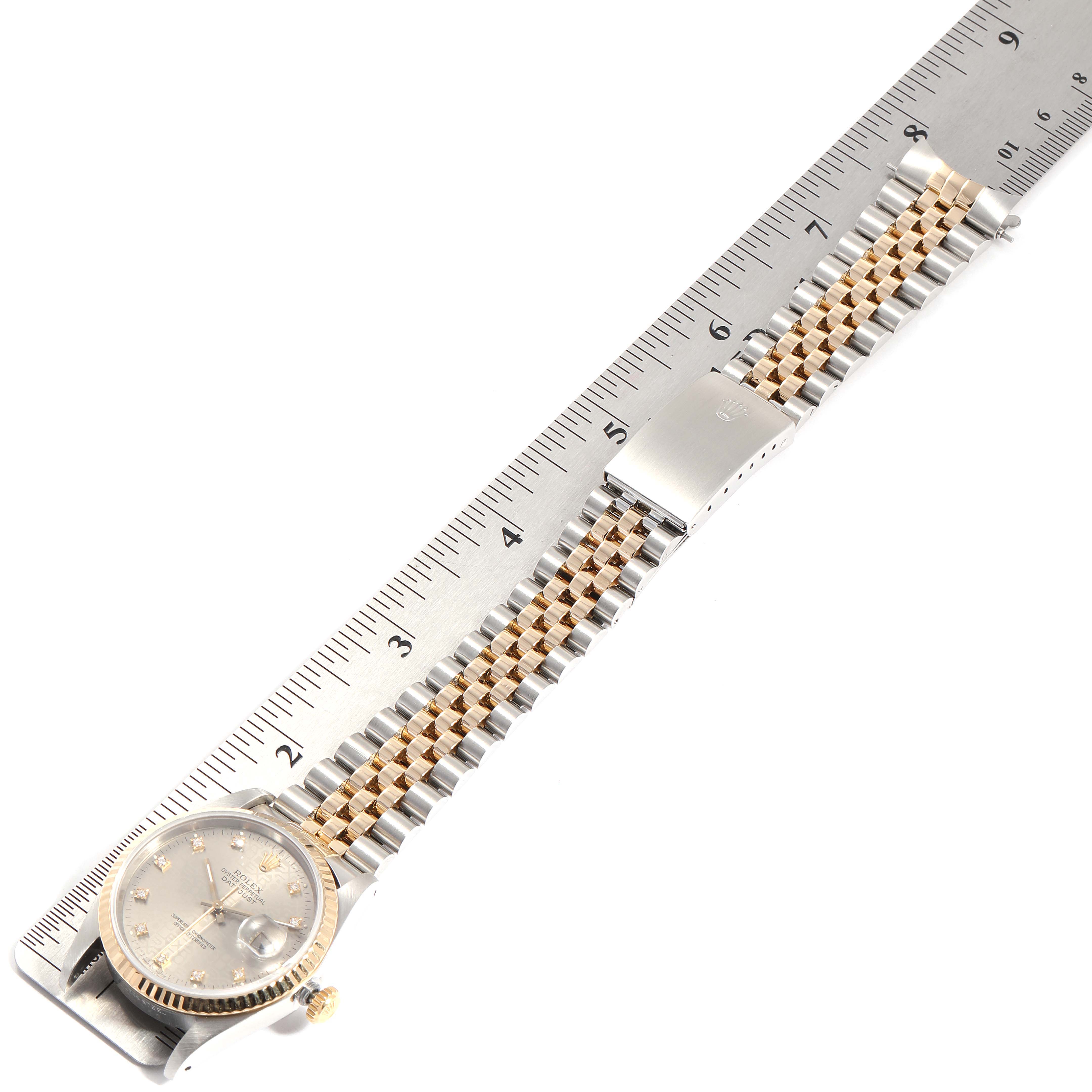 The Datejust Rolex watch is shown from a top view, displaying the dial, bezel, bracelet, and clasp next to a ruler.