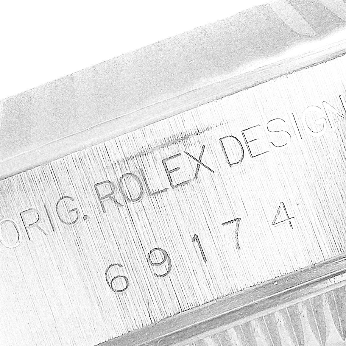 The image shows the engraved side of the case, including the serial number, of a Rolex Datejust 69174 Women's Stainless Steel Black Dial 69174 Women's Stainless Steel Black Dial watch.