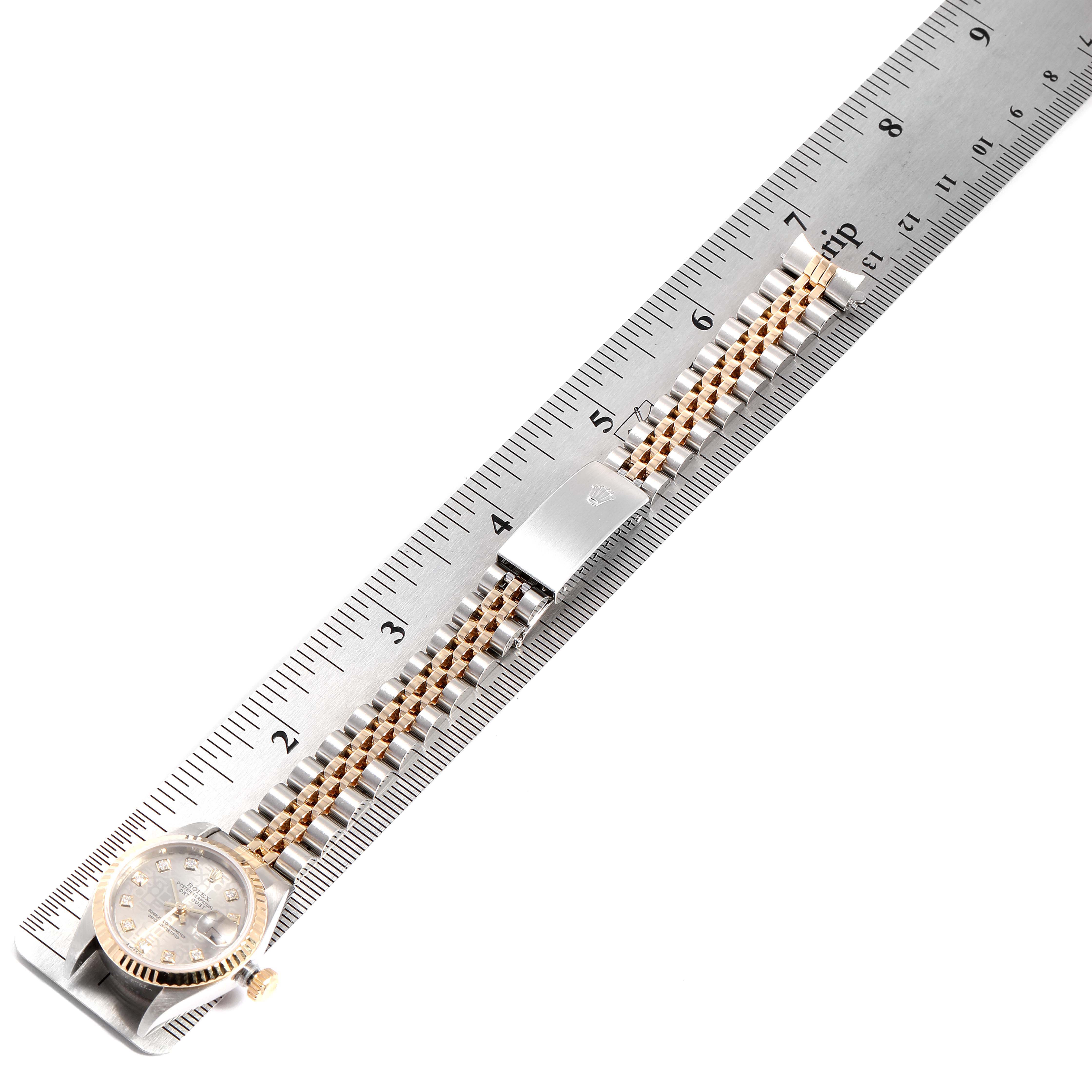 The image shows a top view of a Rolex Datejust 79173 Women
s Steel and Gold (two tone) Silver Dial 79173 Women
s Steel and Gold (two tone) Silver Dial watch placed next to a ruler, highlighting its bracelet and clasp.
