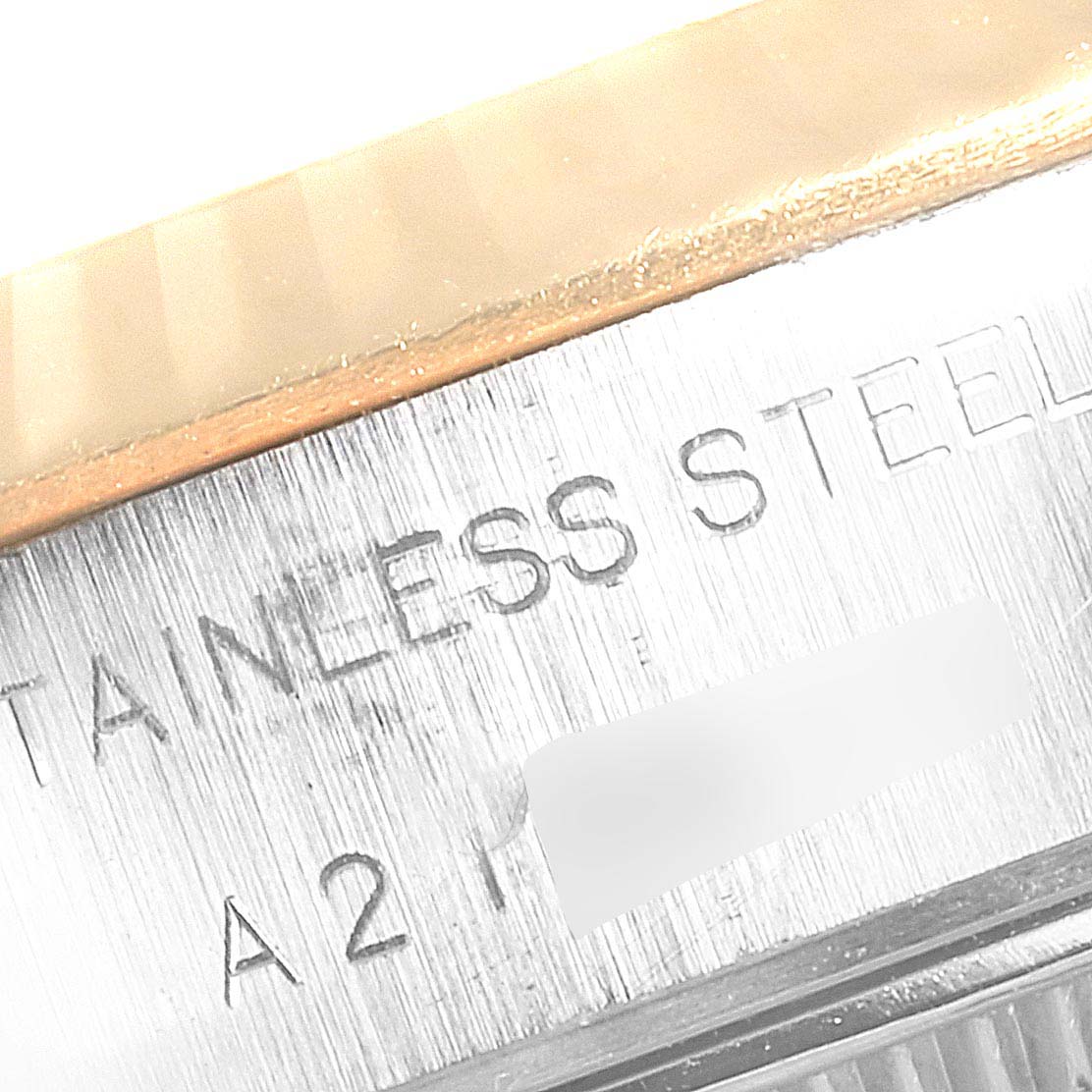 This close-up image showcases part of the side and engraved text on a Rolex Datejust 79173  Women
s Steel and Gold (two tone) Champagne Dial 79173  Women
s Steel and Gold (two tone) Champagne Dial watch, specifically highlighting the "STAINLESS STEEL" inscription.