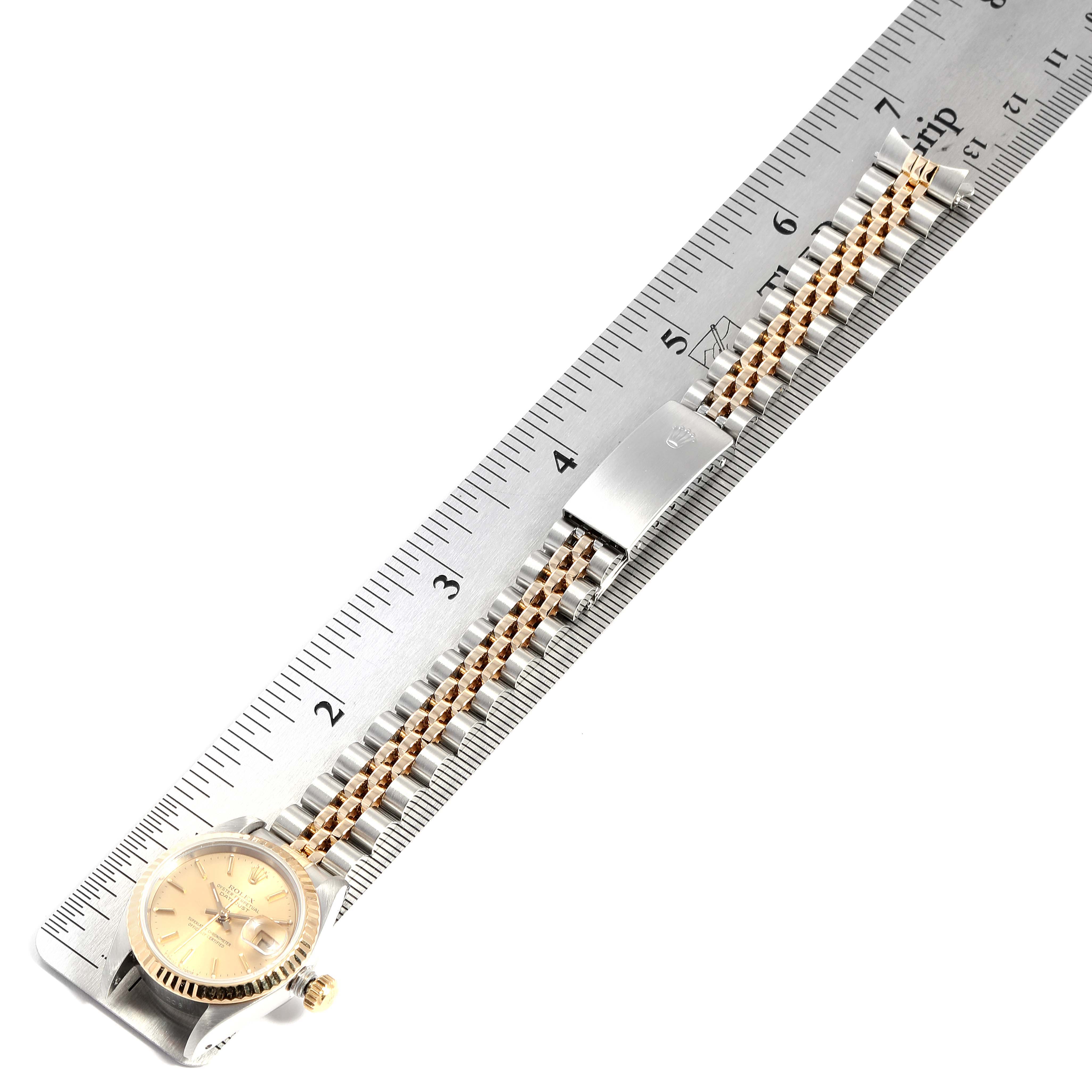 The image shows a Rolex Datejust 69173 Women
s Steel and Gold (two tone) Champagne Dial 69173 Women
s Steel and Gold (two tone) Champagne Dial watch laid flat against a ruler, displaying its face, bracelet, and clasp.