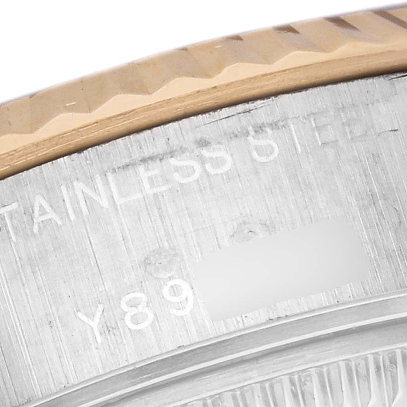The image shows a close-up of the Rolex Datejust 79173 Women's Steel and Gold (two tone) Silver Dial 79173 Women's Steel and Gold (two tone) Silver Dial watch bezel and part of the stainless steel case with engraved text.