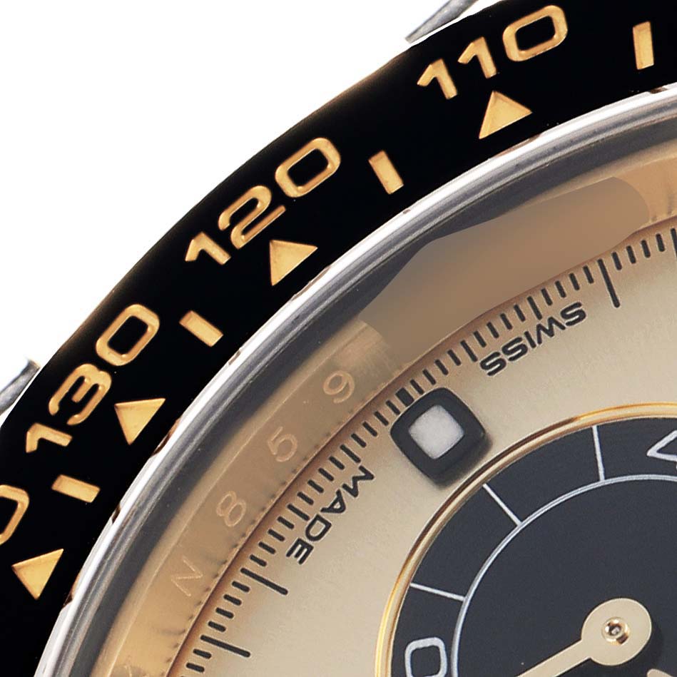 The image shows a close-up of the bezel and dial of a Rolex Daytona 116518 Men
s Yellow Gold Champagne Dial, featuring the tachymetric scale and part of the watch face.