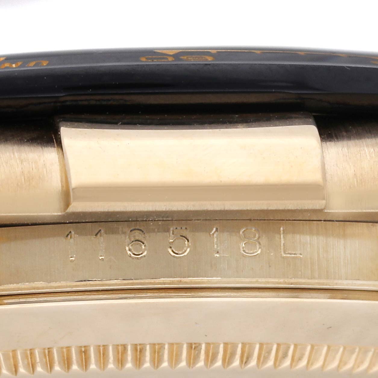This image shows a close-up of the side of a Rolex Daytona 116518L Men's Yellow Gold Black Dial 116518L Men's Yellow Gold Black Dial watch, highlighting the case edge and part of the serial number engraved.