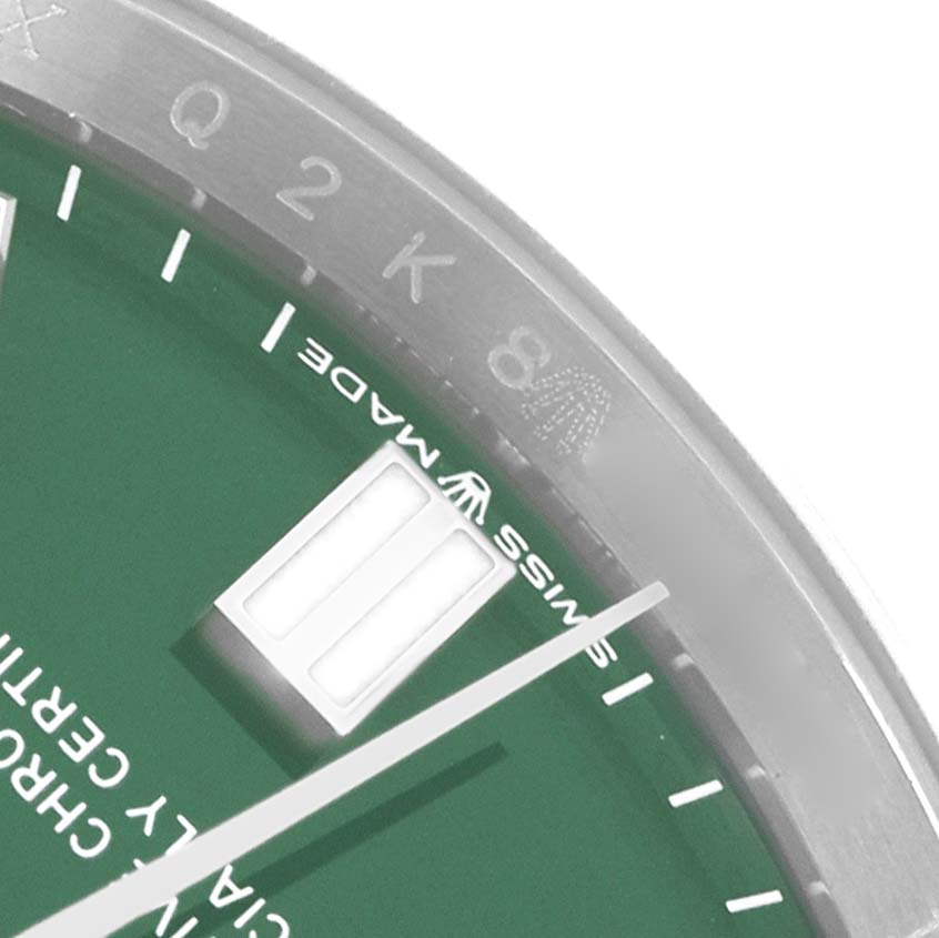 The image shows a close-up of a Rolex Oyster Perpetual 126000 Men
s Stainless Steel Green Dial with green dial, including part of the bezel and hour markers.