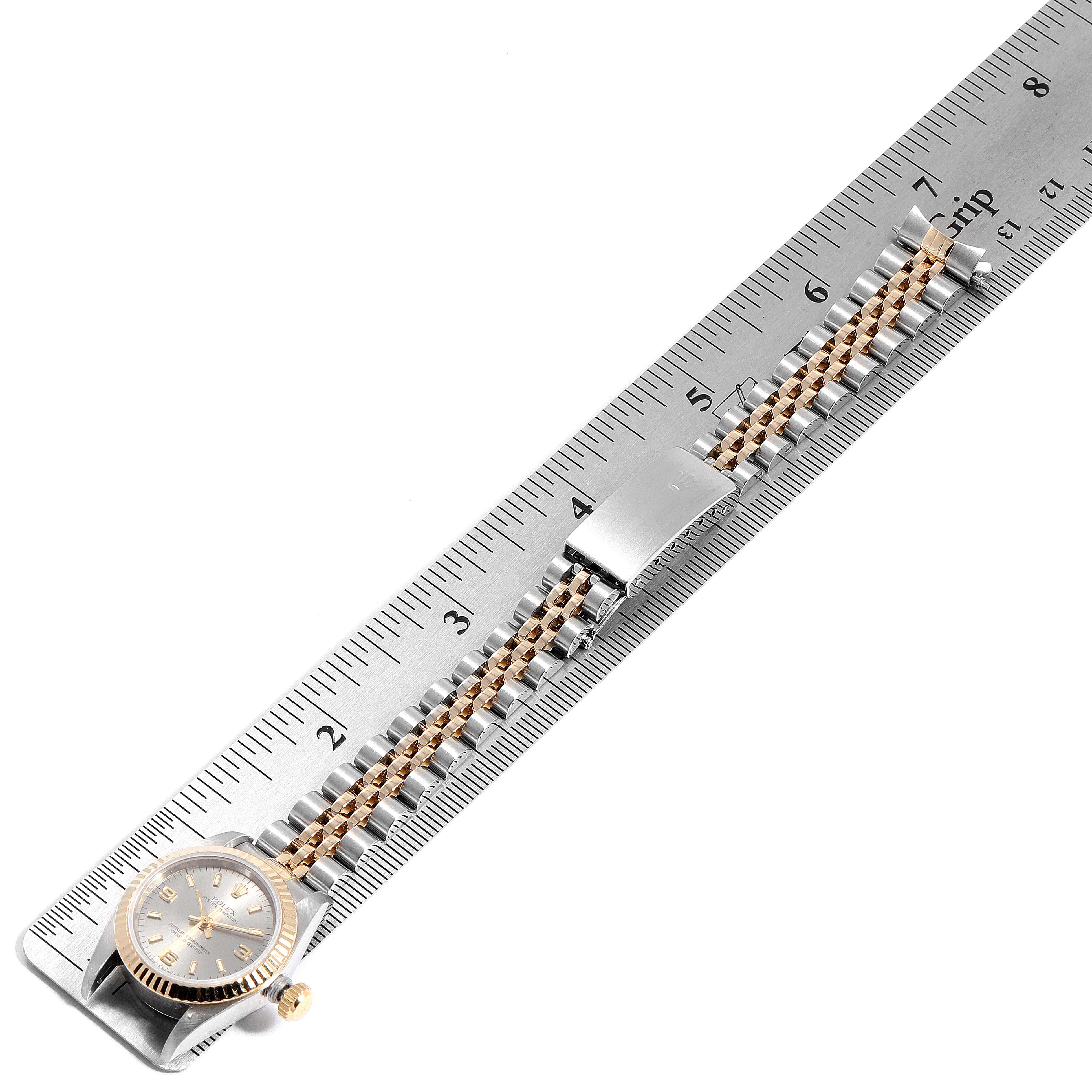 The image shows a Rolex Oyster Perpetual 67193 Women's Steel and Gold (two tone) Grey Dial 67193 Women's Steel and Gold (two tone) Grey Dial watch laid flat next to a ruler, displaying its face, bracelet, and clasp.