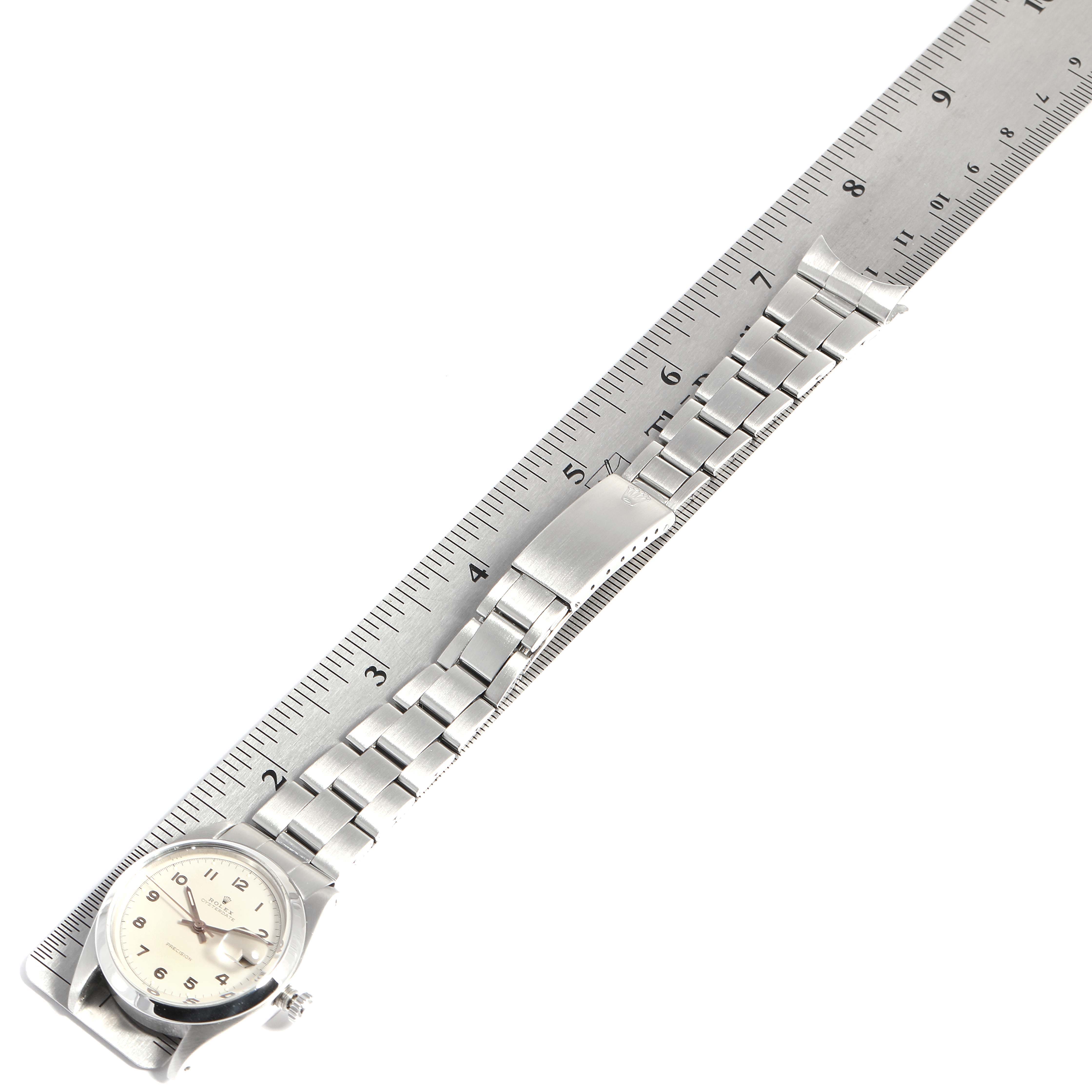 The image shows a Rolex Vintage Collection 6694 Men's Stainless Steel Silver Dial 6694 Men's Stainless Steel Silver Dial watch flat, face-up, with its metal bracelet laid out next to a ruler for scale.